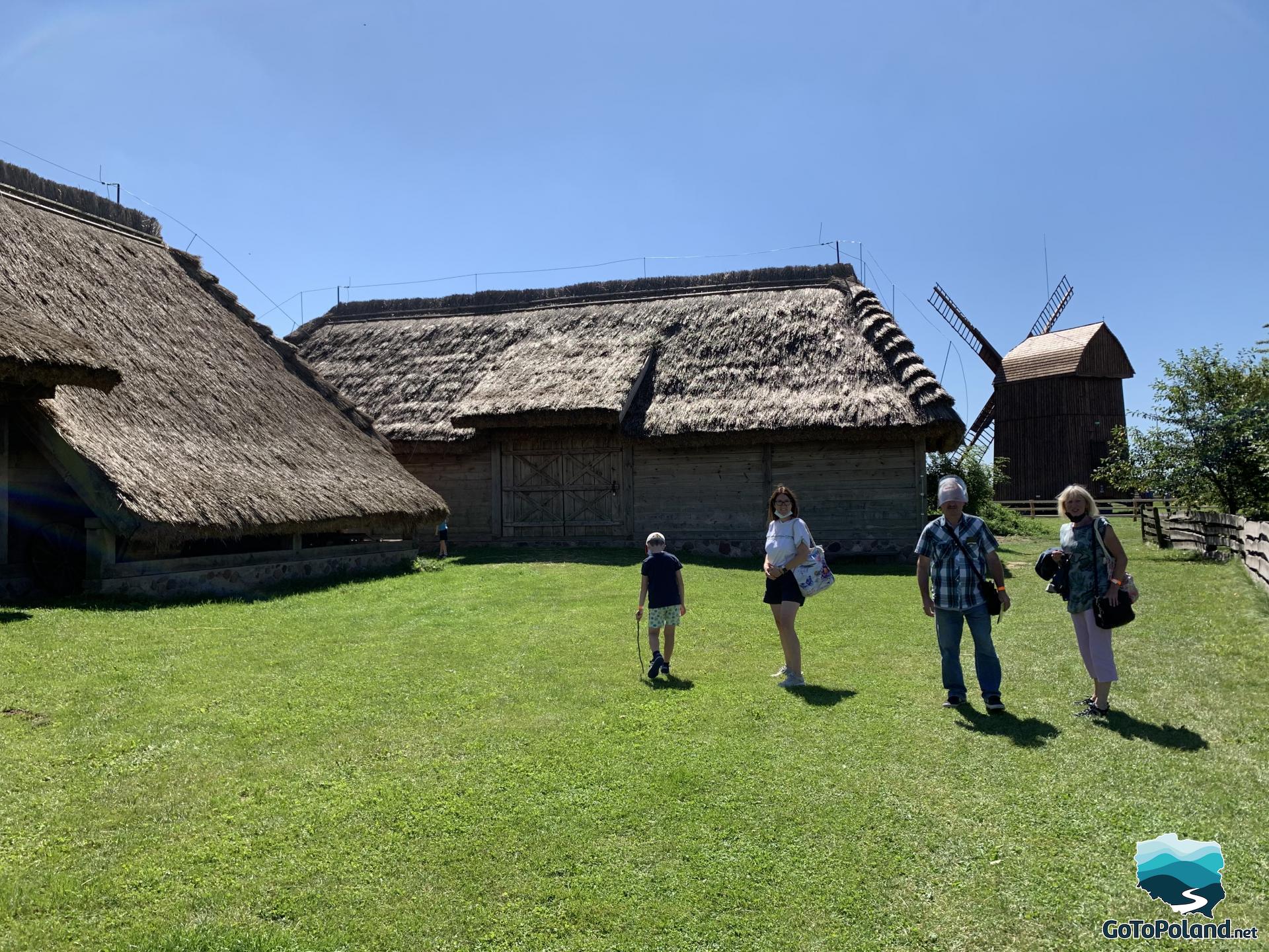 a landscape with peasant huts and a windmill in the background, the family is standing in the middle of a lawn