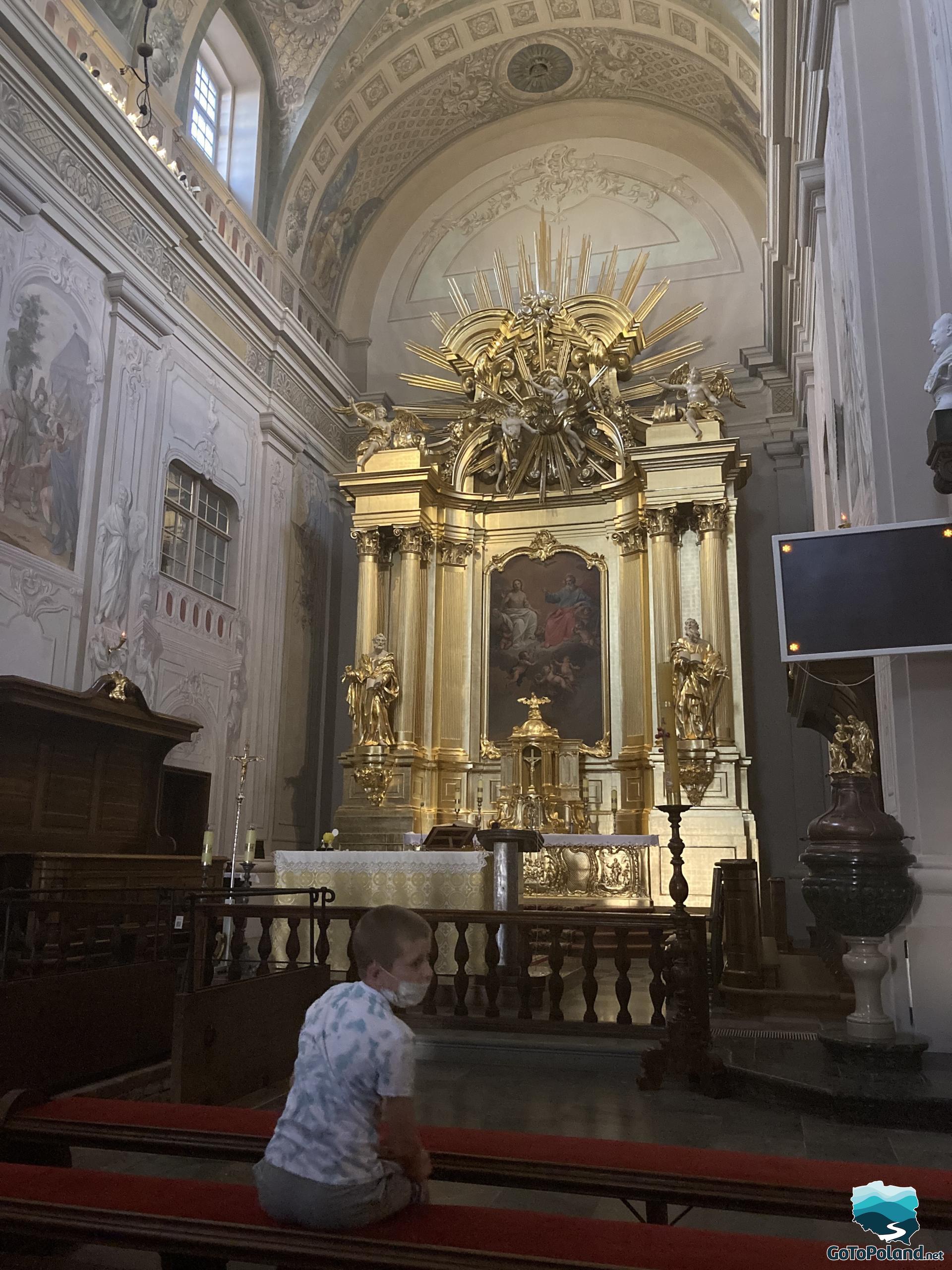 the main golden altar in the church, the boy is sitting in the pew