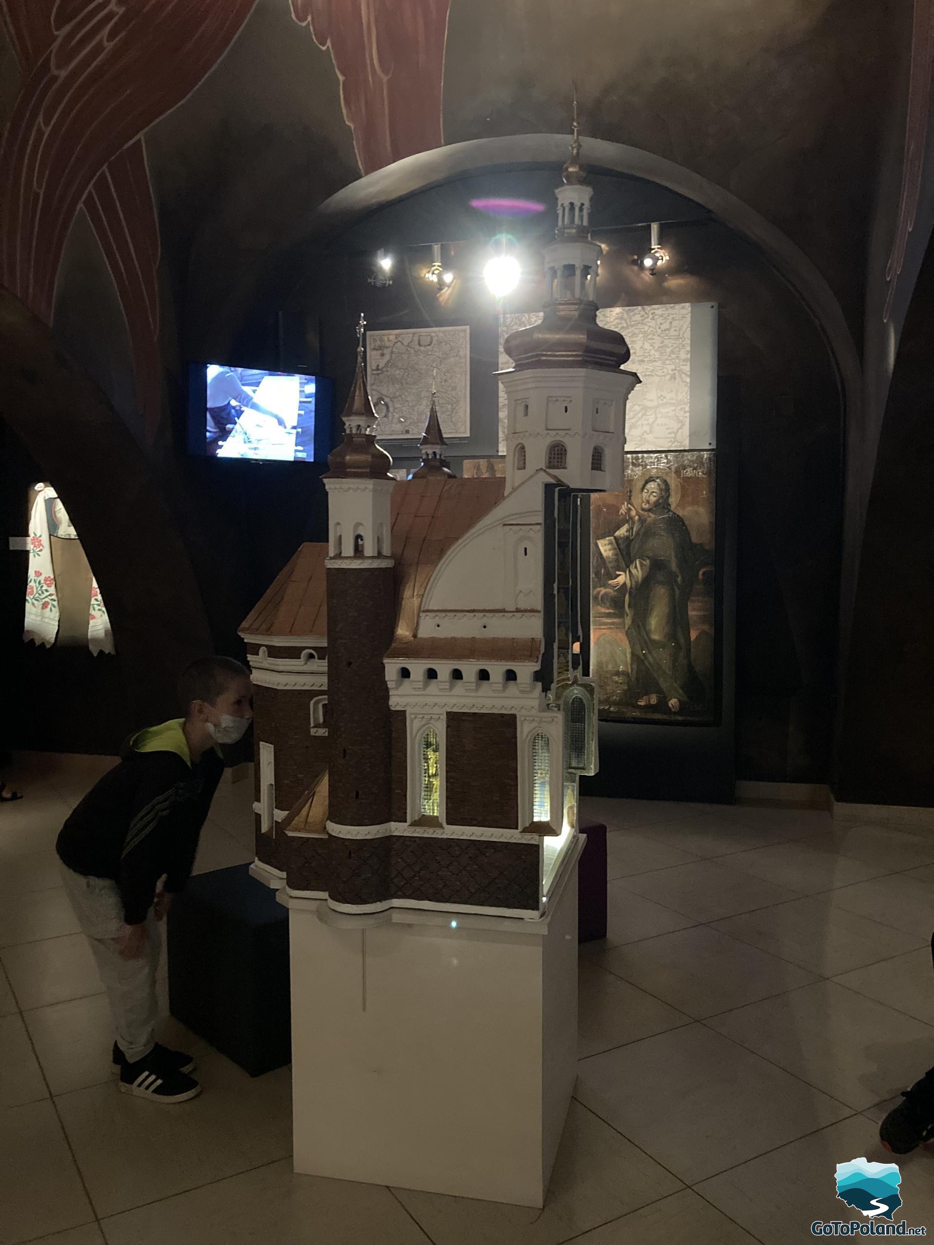 the boy is looking at the model of the monastery