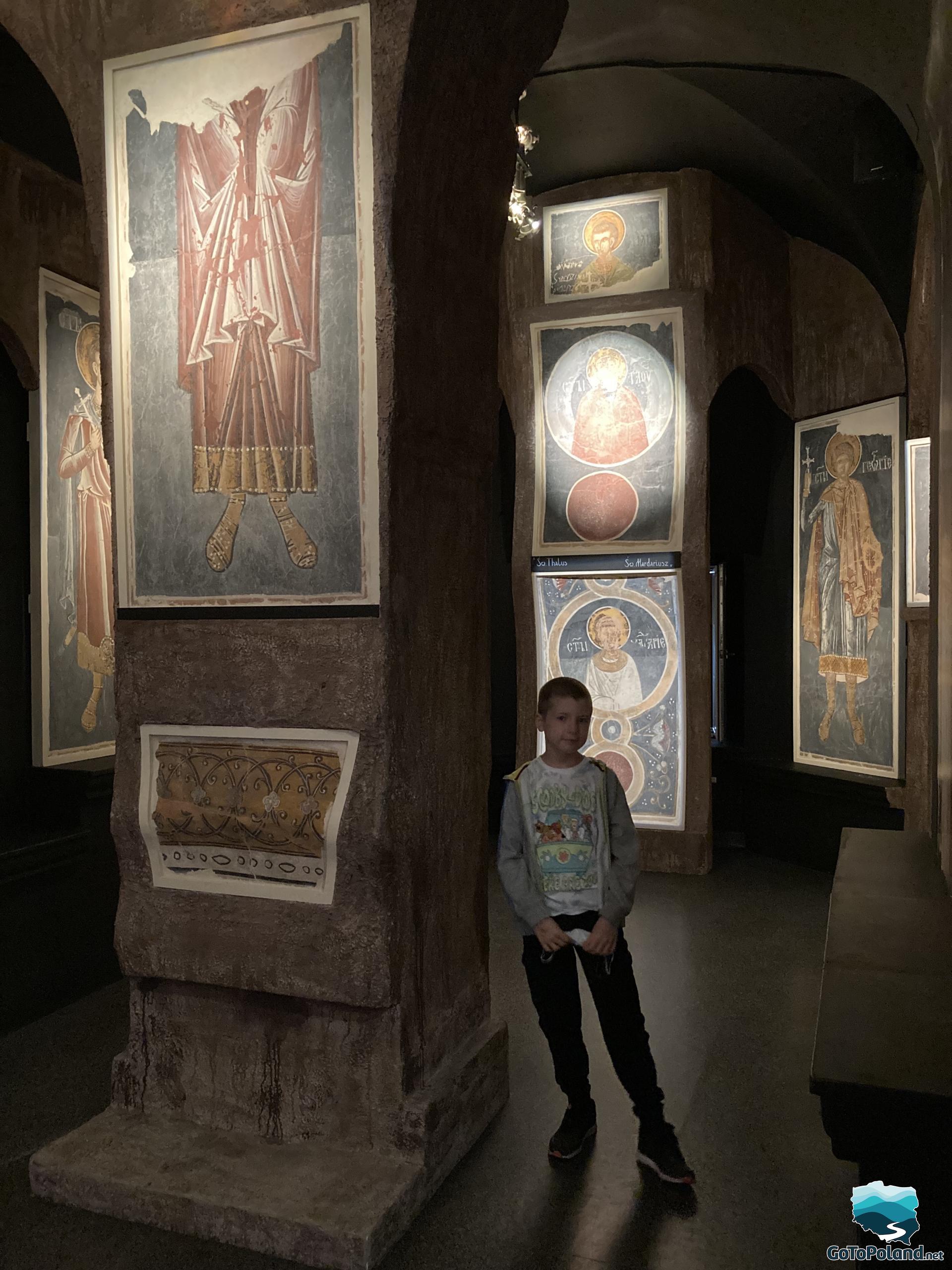 the boy is standing by the large poles on which the icons are hung