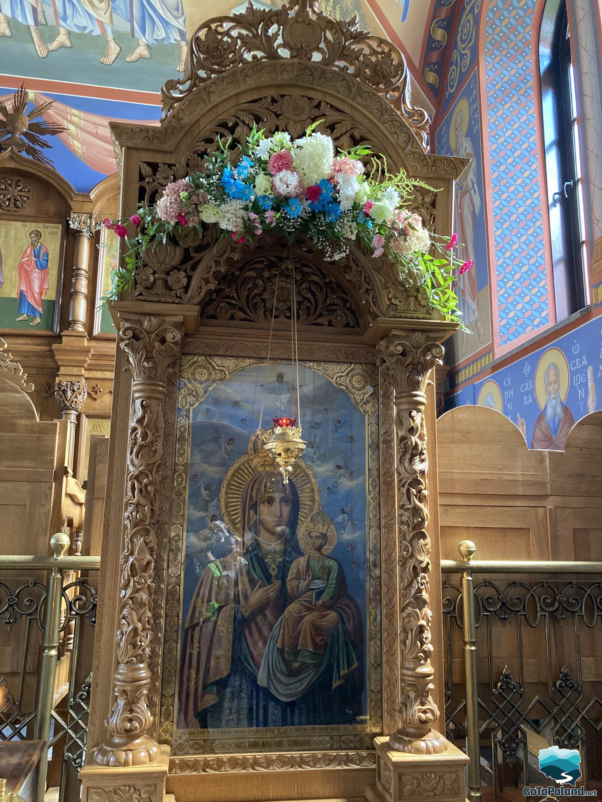 an image of the Mother of God behind glass, placed on a wooden altar