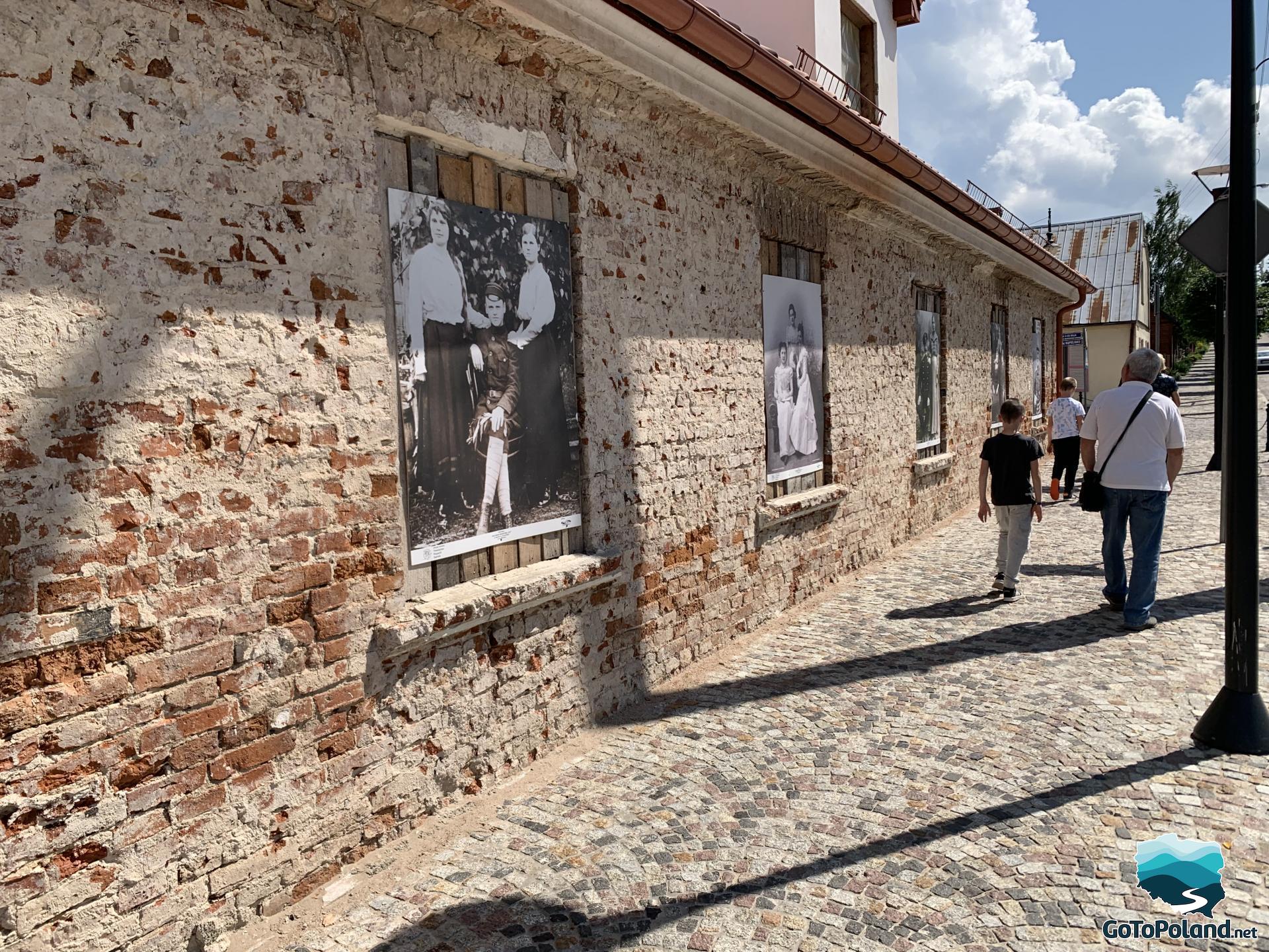 on the old brick building there are huge black-and-white photos depicting the former inhabitants of the town