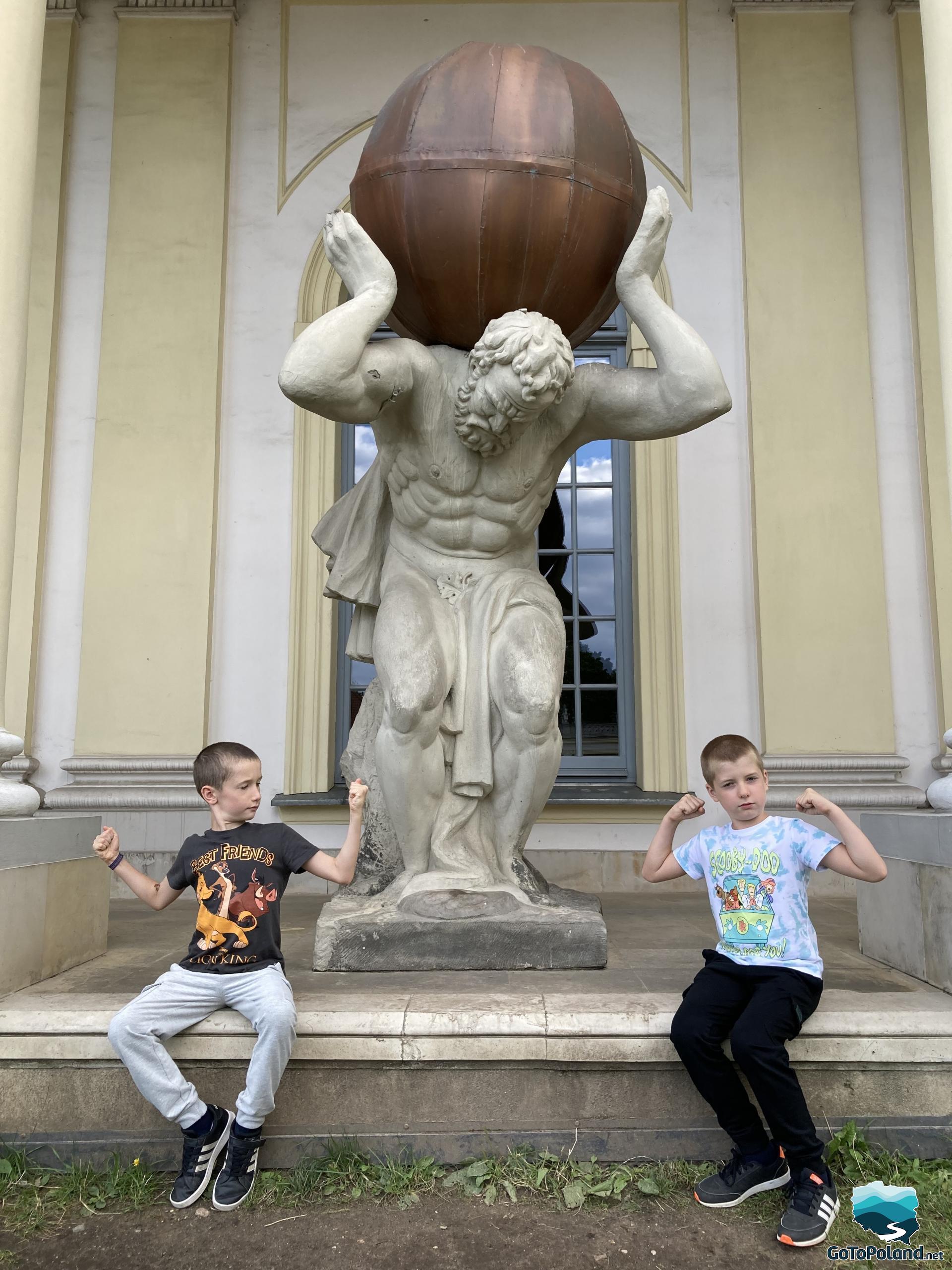 a statue of Sisyphus and two boys who flex their biceps to show that they are strong too