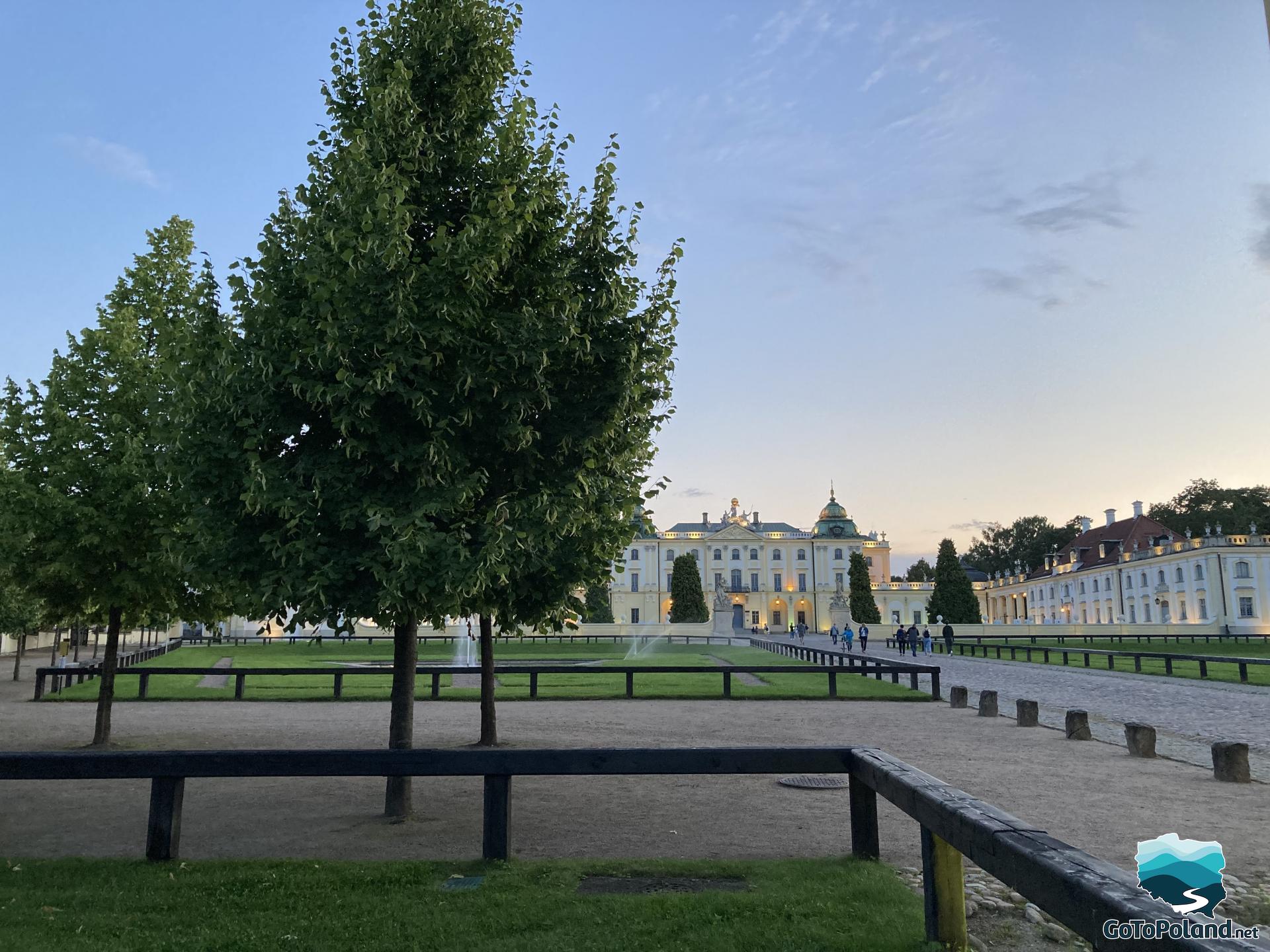 small trees in the foreground, a palace in the background