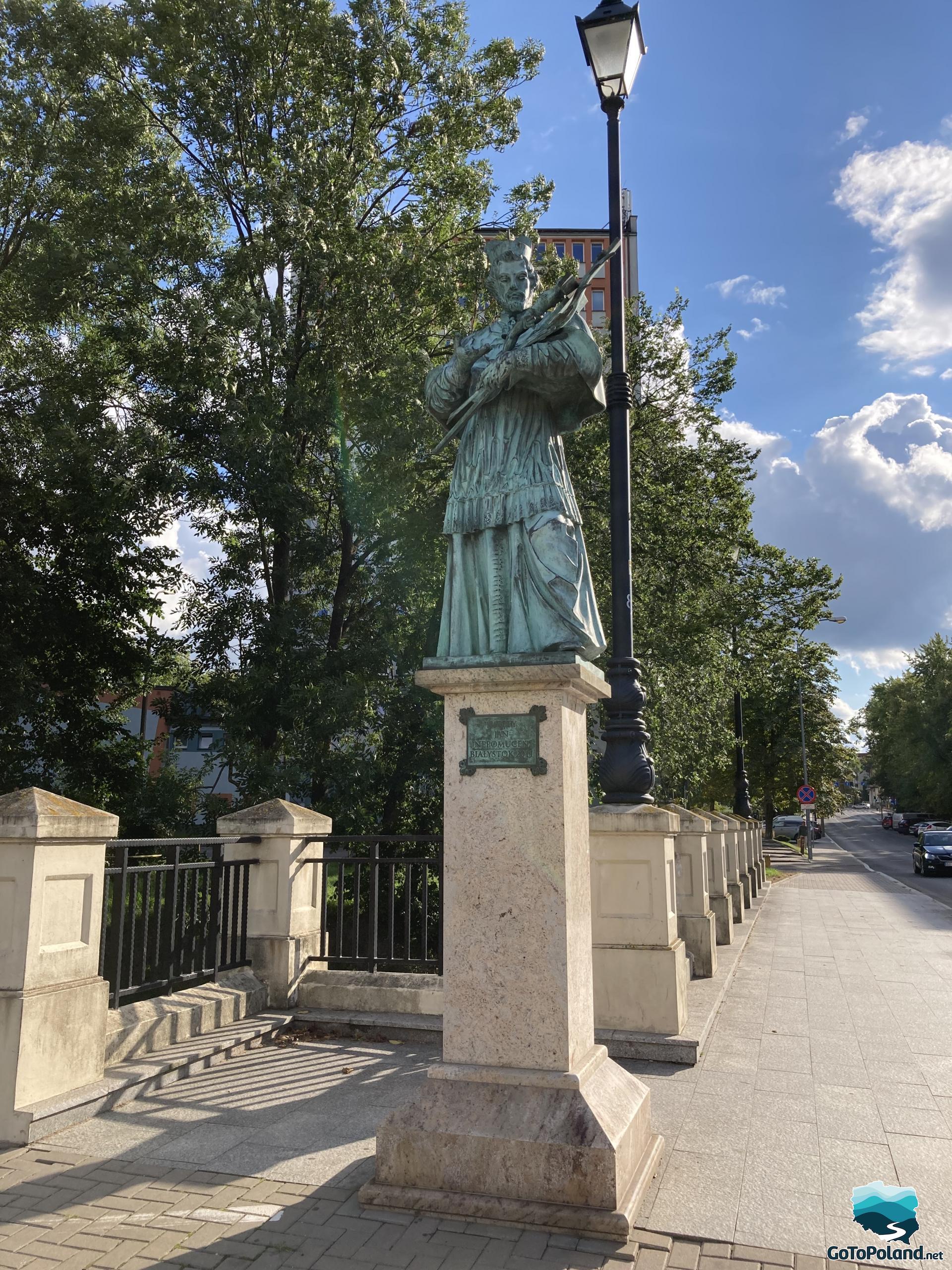 a statue of John of Nepomuk on a pedestal stands on the street