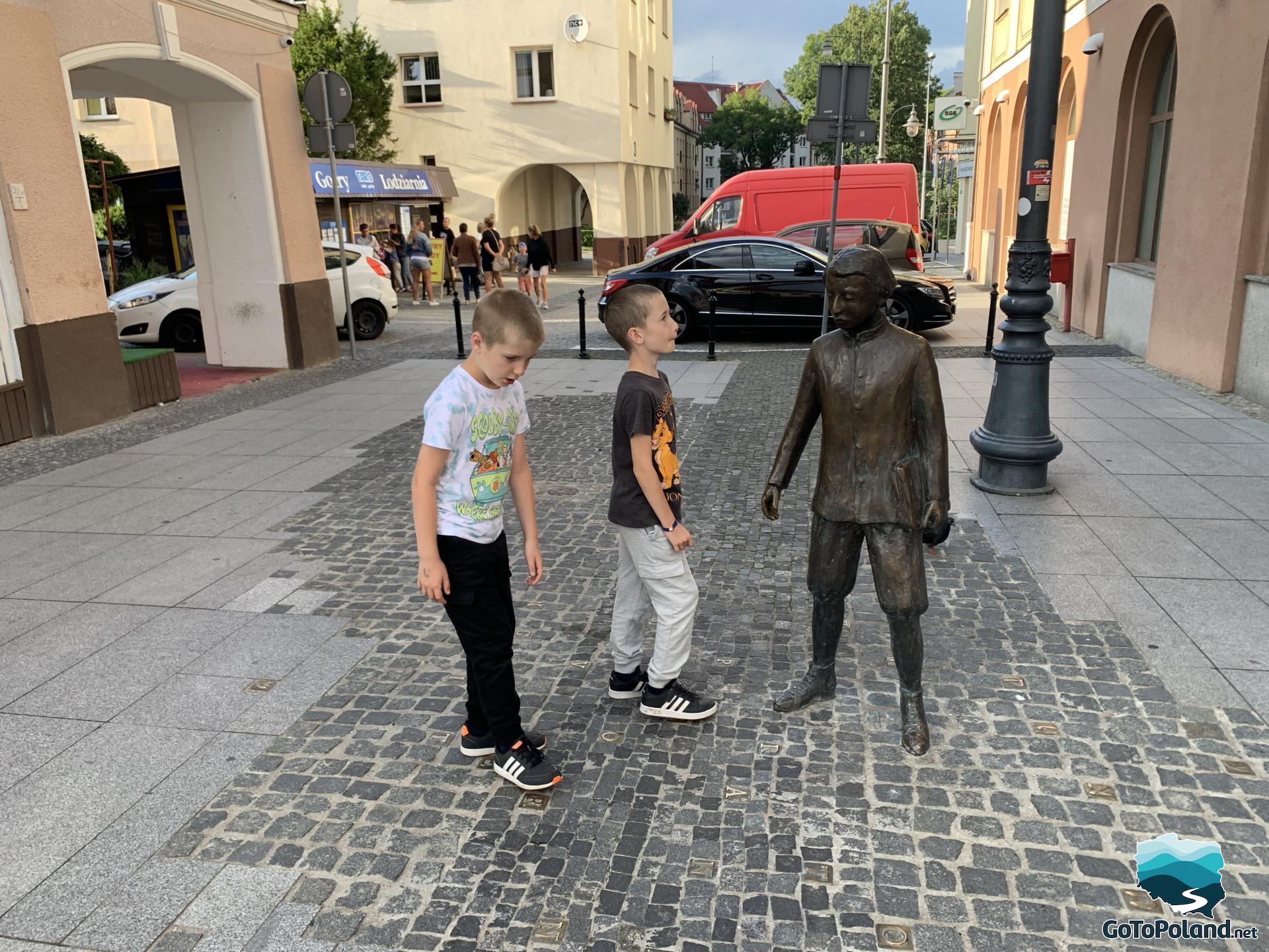 two boys are near the statue of the little man who was the creator of the Esperanto language