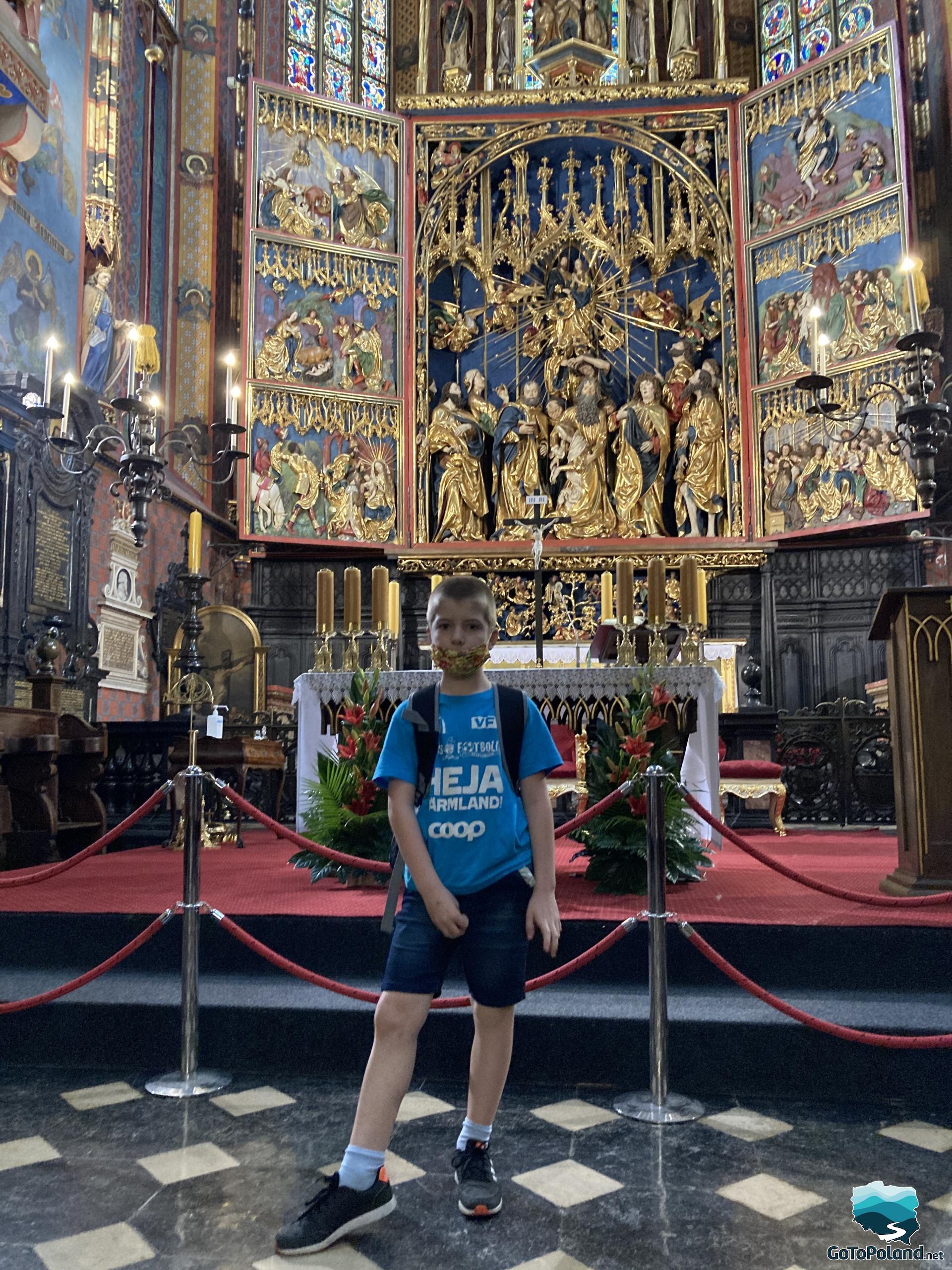 a boy is standing in front of the golden altar