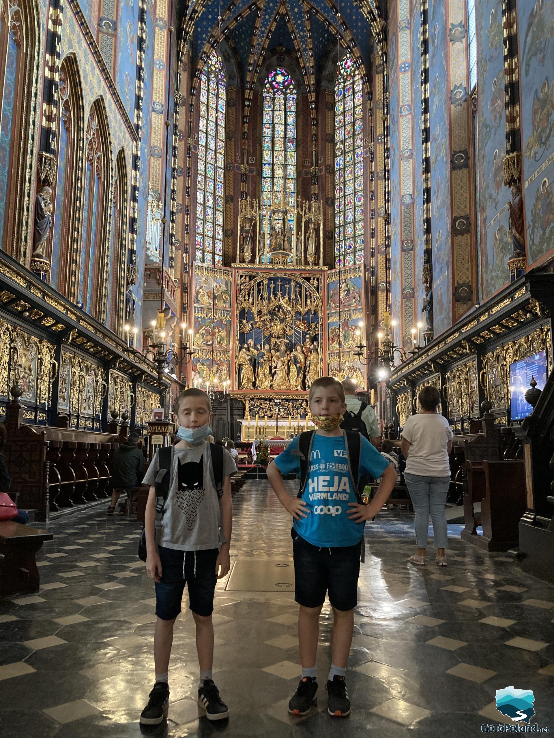 two boys are standing in front of the golden altar