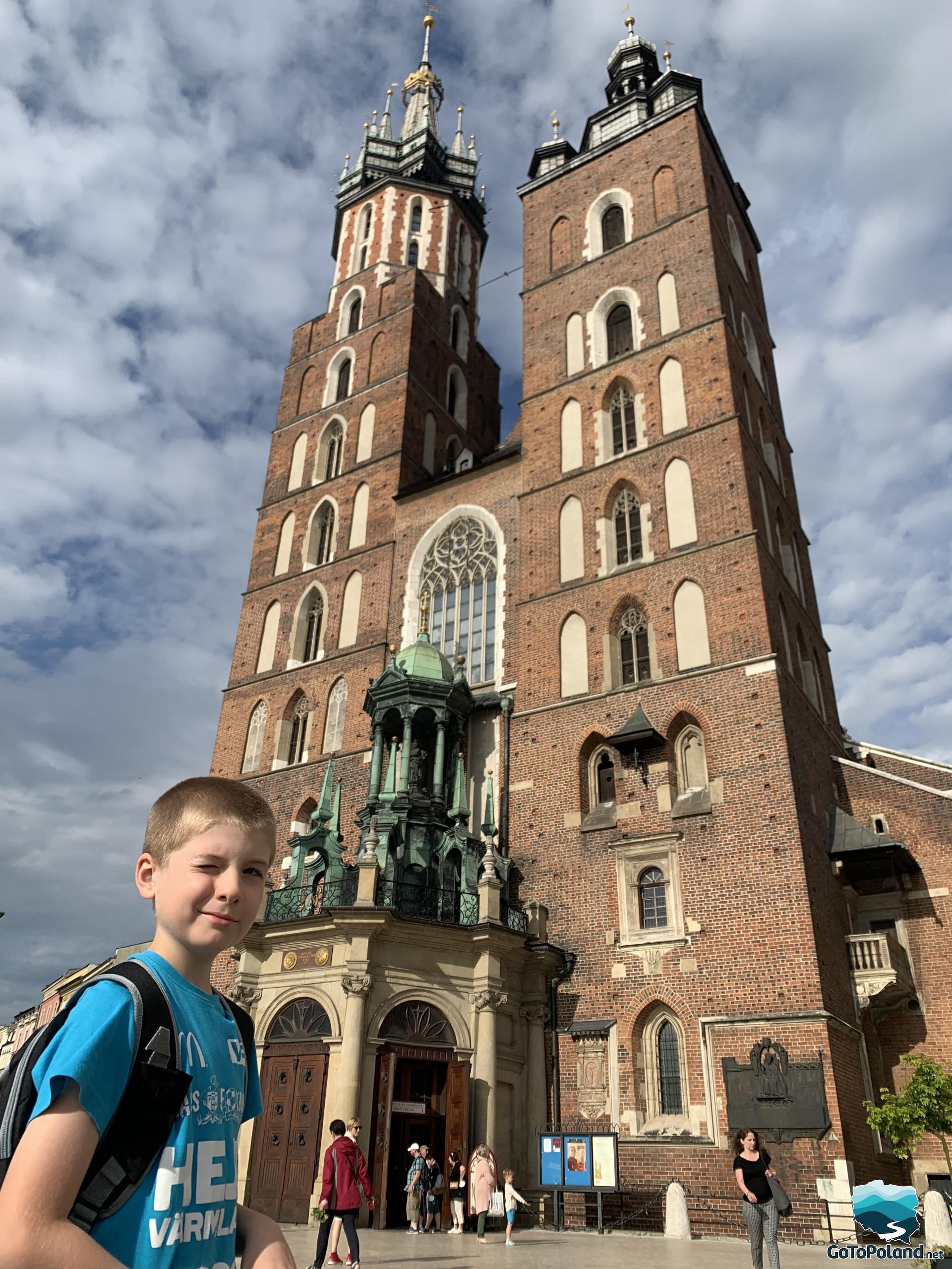 a boy and gothic church behind him, photo taken close up