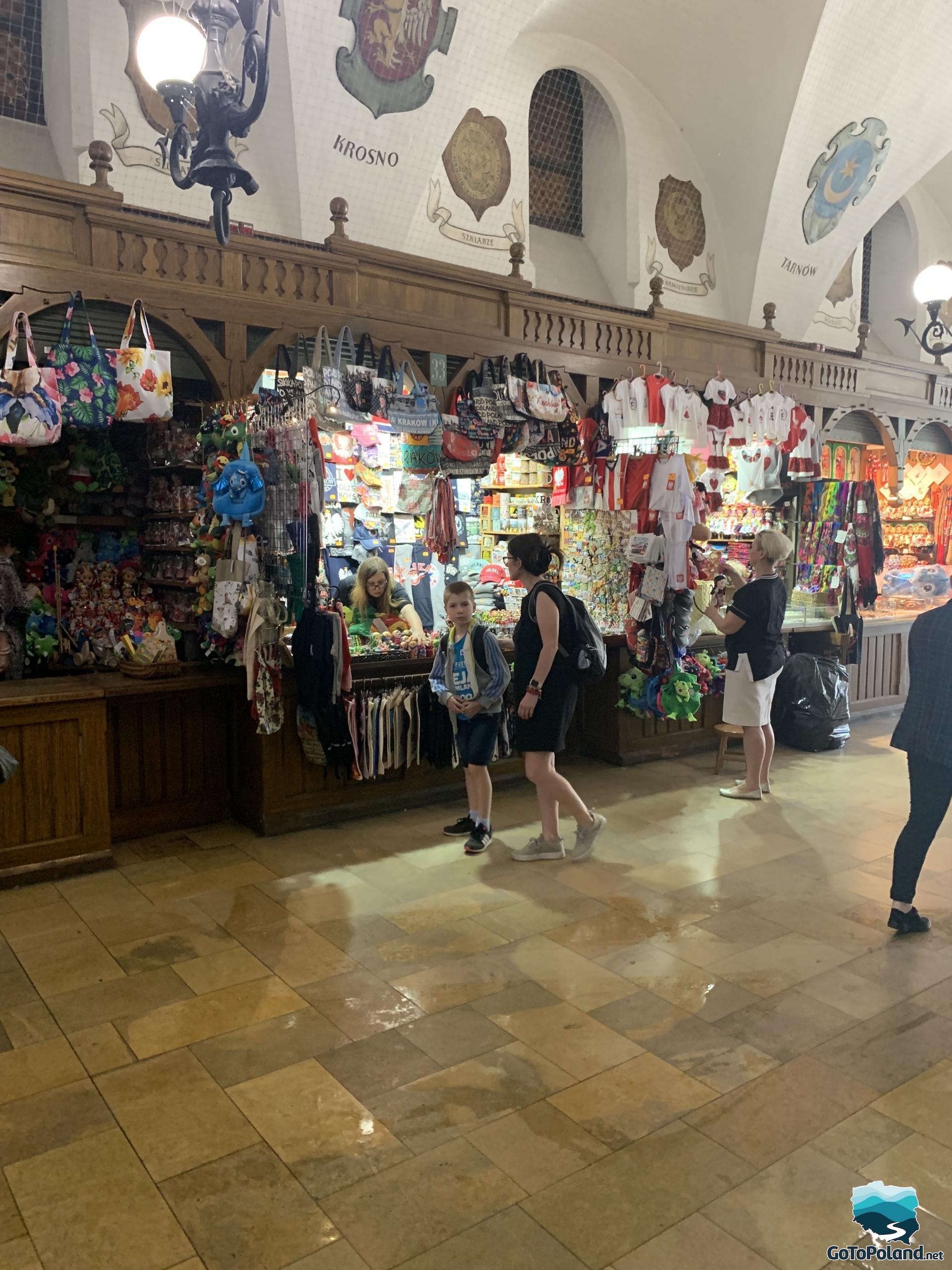 a boy and a woman are inside the Cloth Hall and they are watching souvenirs