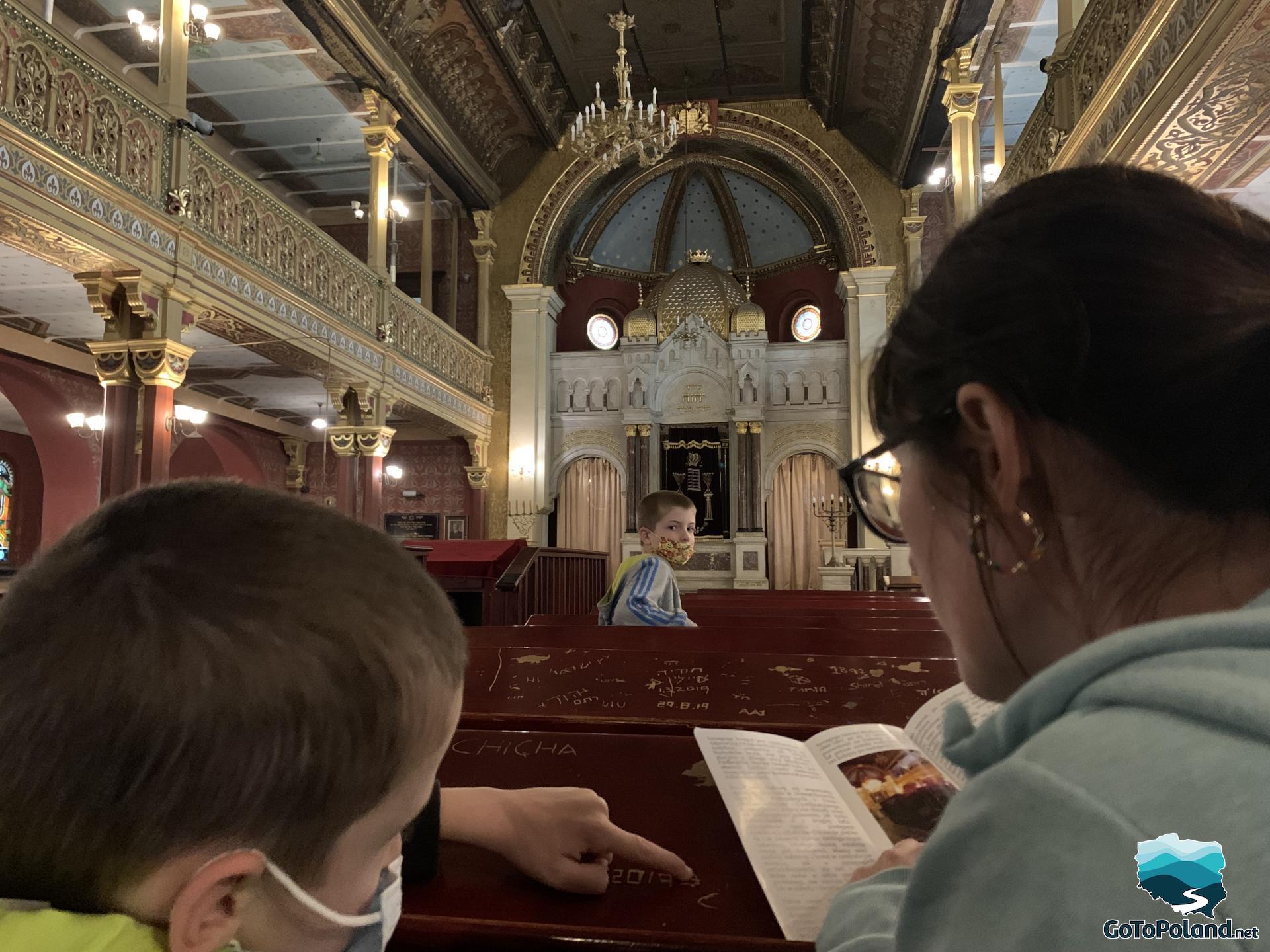 a woman and two boys are sitting in a pew in a synagogue 