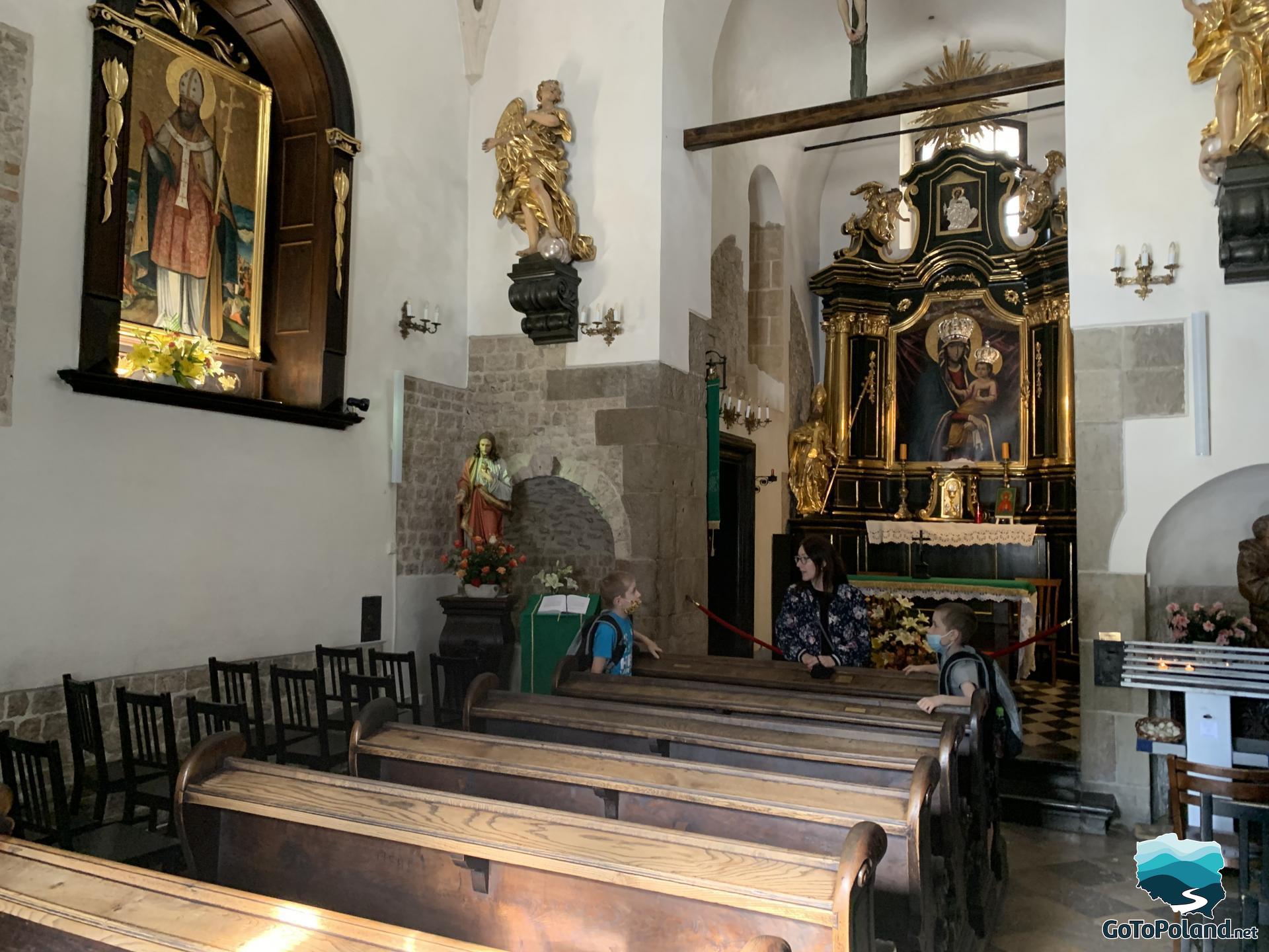 a woman and two boys are inside the church, behind them there is an altar 