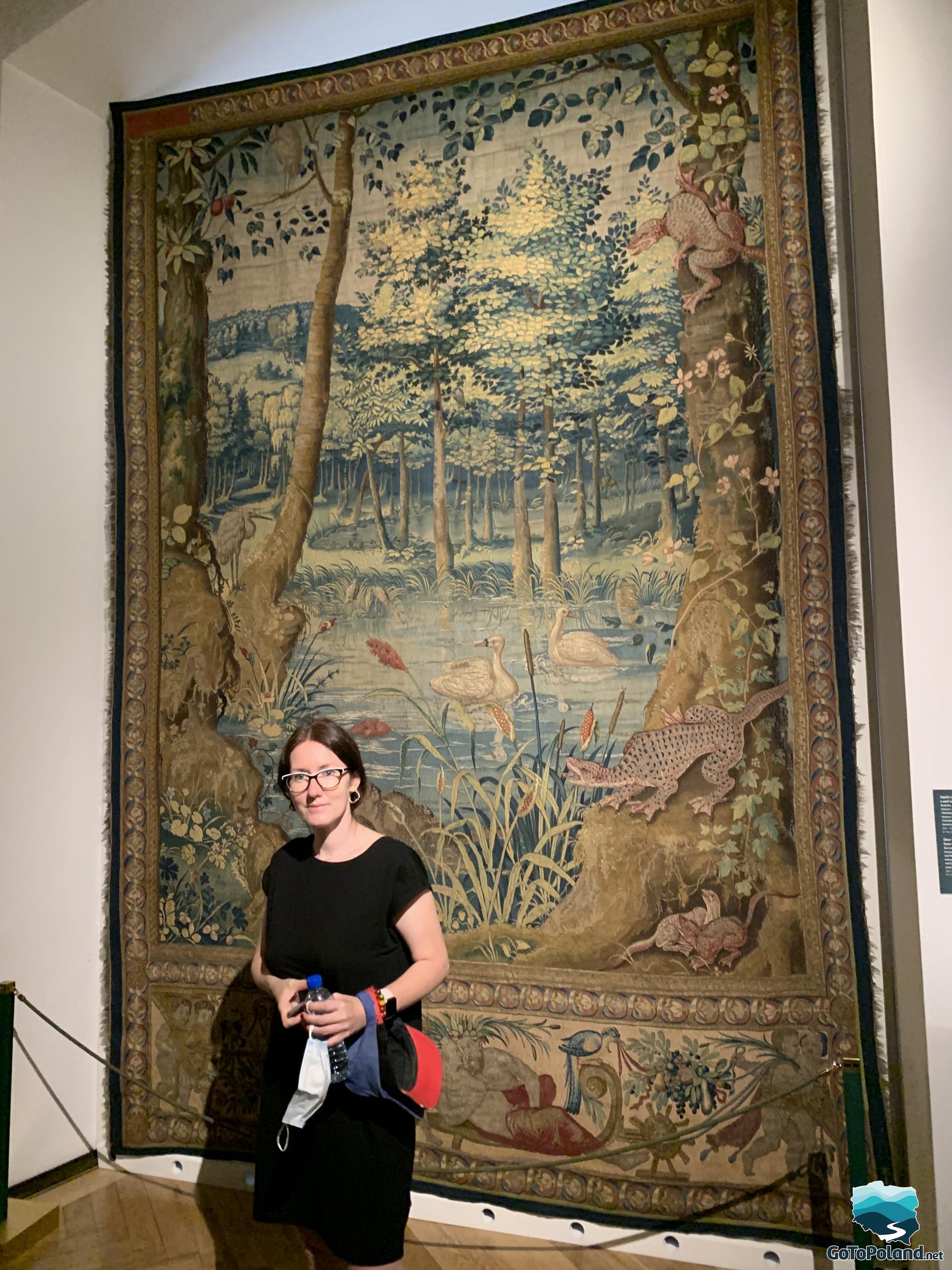 a woman is standing by a tapestry with wild animals