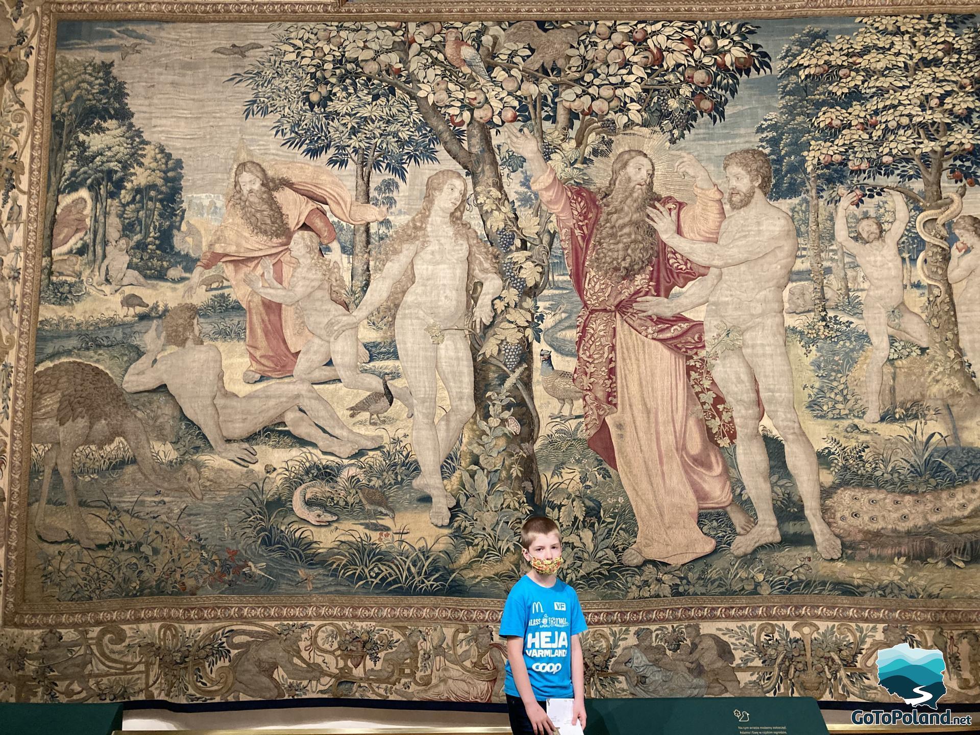 a boy is standing in front of the tapestry, on the tapestry is a religious scene