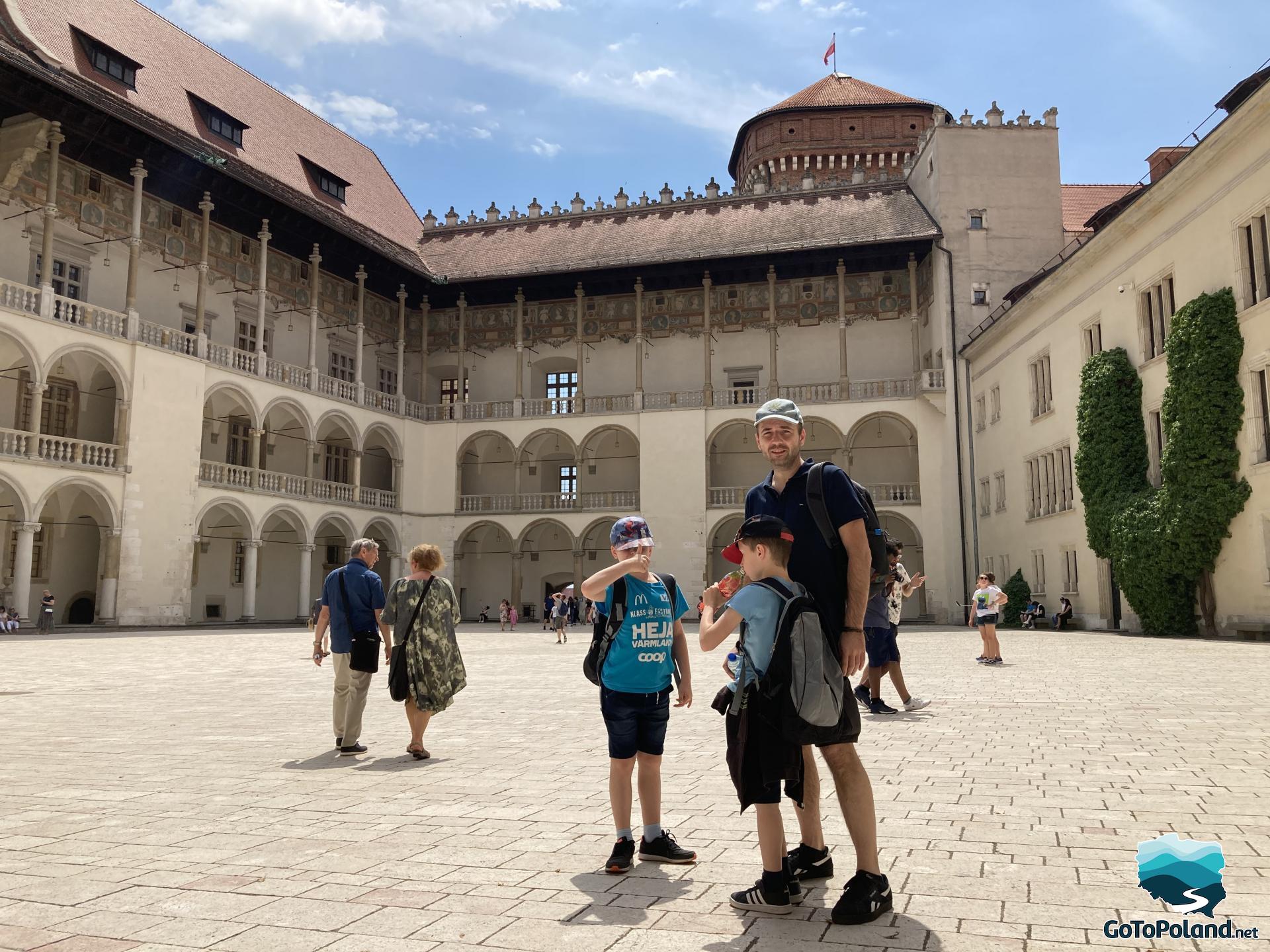 a man and two kids standing  in the courtyard of the castle