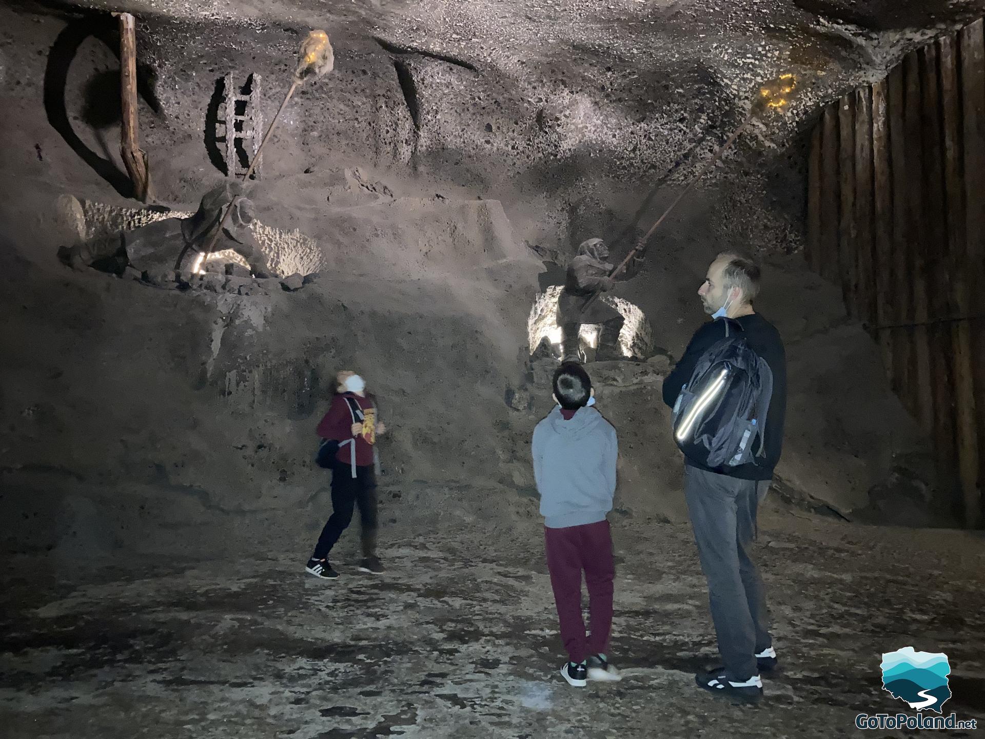 two boys and a man are in a salt mine, they are watching carved salt figures 