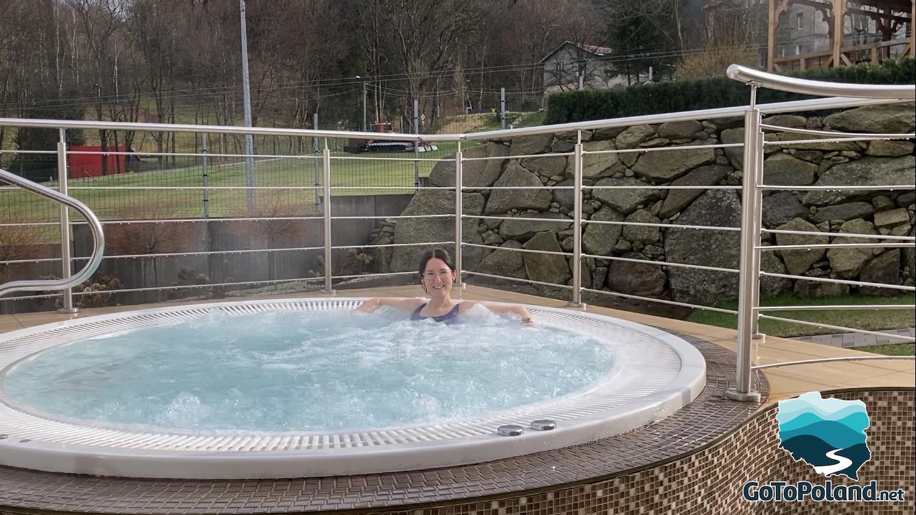 a woman sitting in an outdoor Jacuzzi 