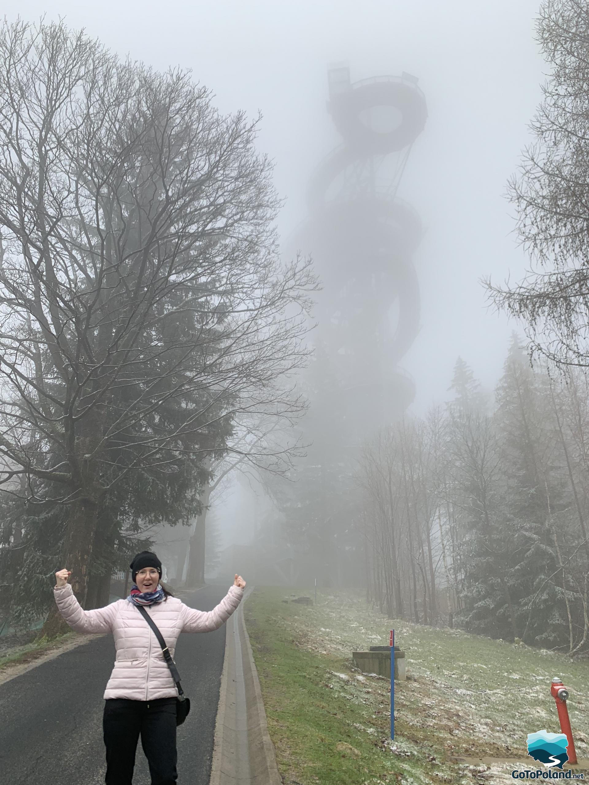 the highest observation tower emerges from the mist, in front of which a woman is standing  
