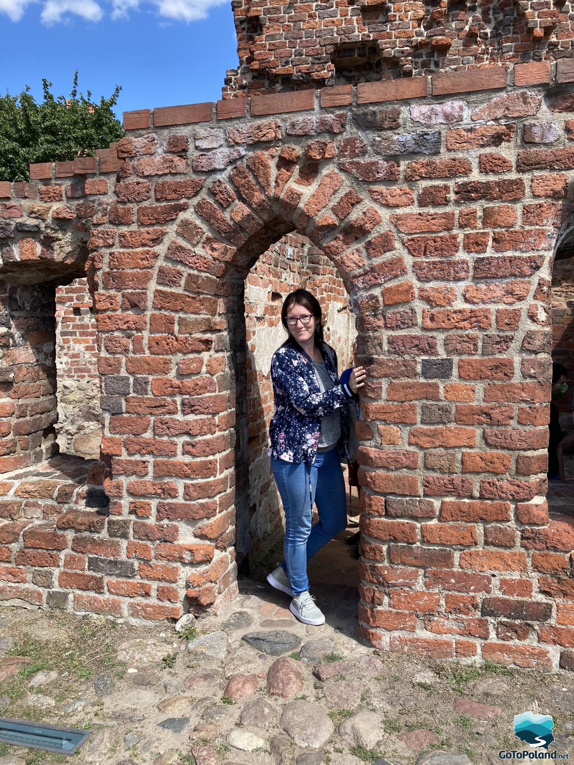 a woman is standing in the entrance to the ruins of a former red brick castle