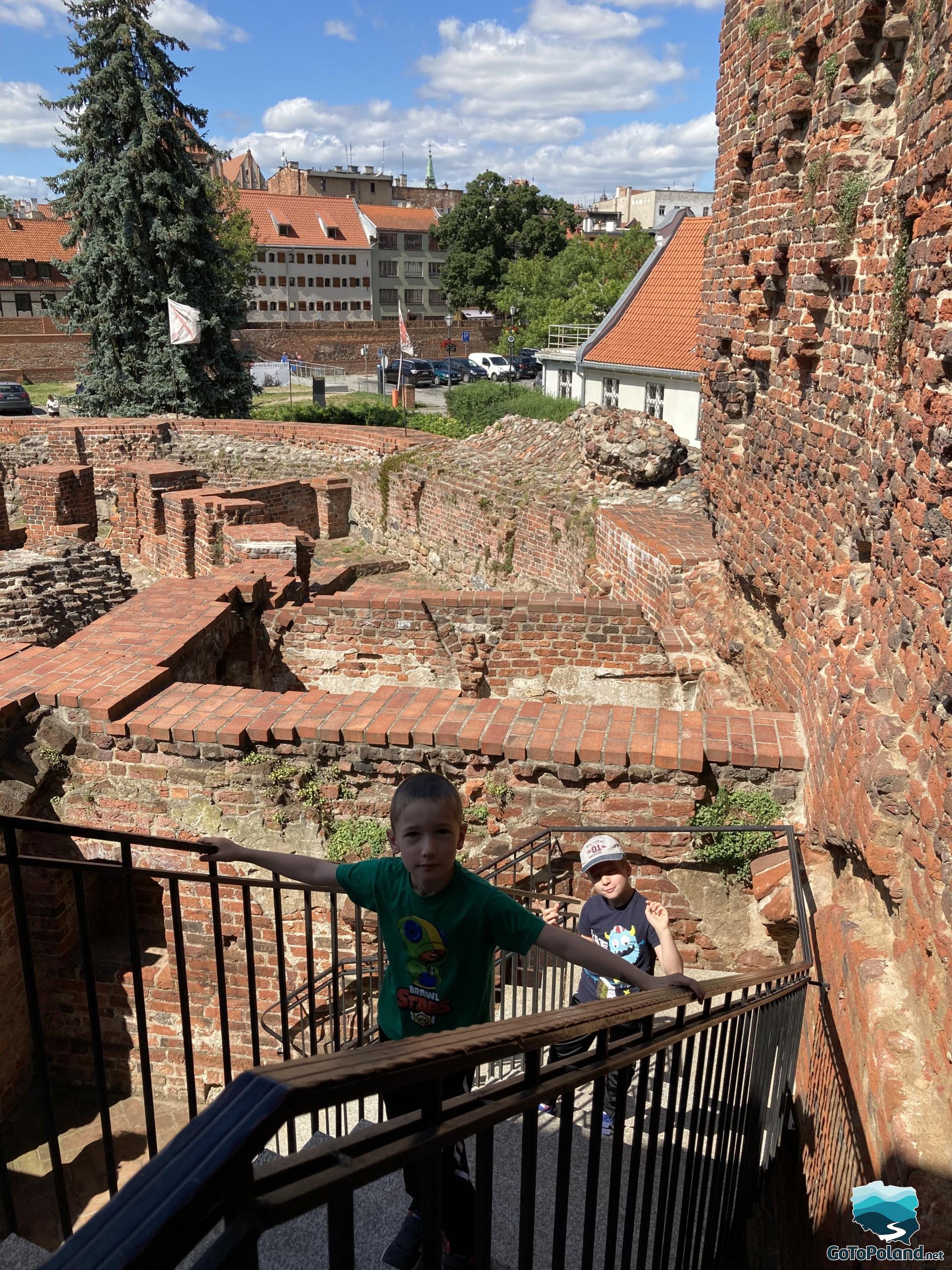 two children are climbing on the stairs to the ruins of a former red brick castle