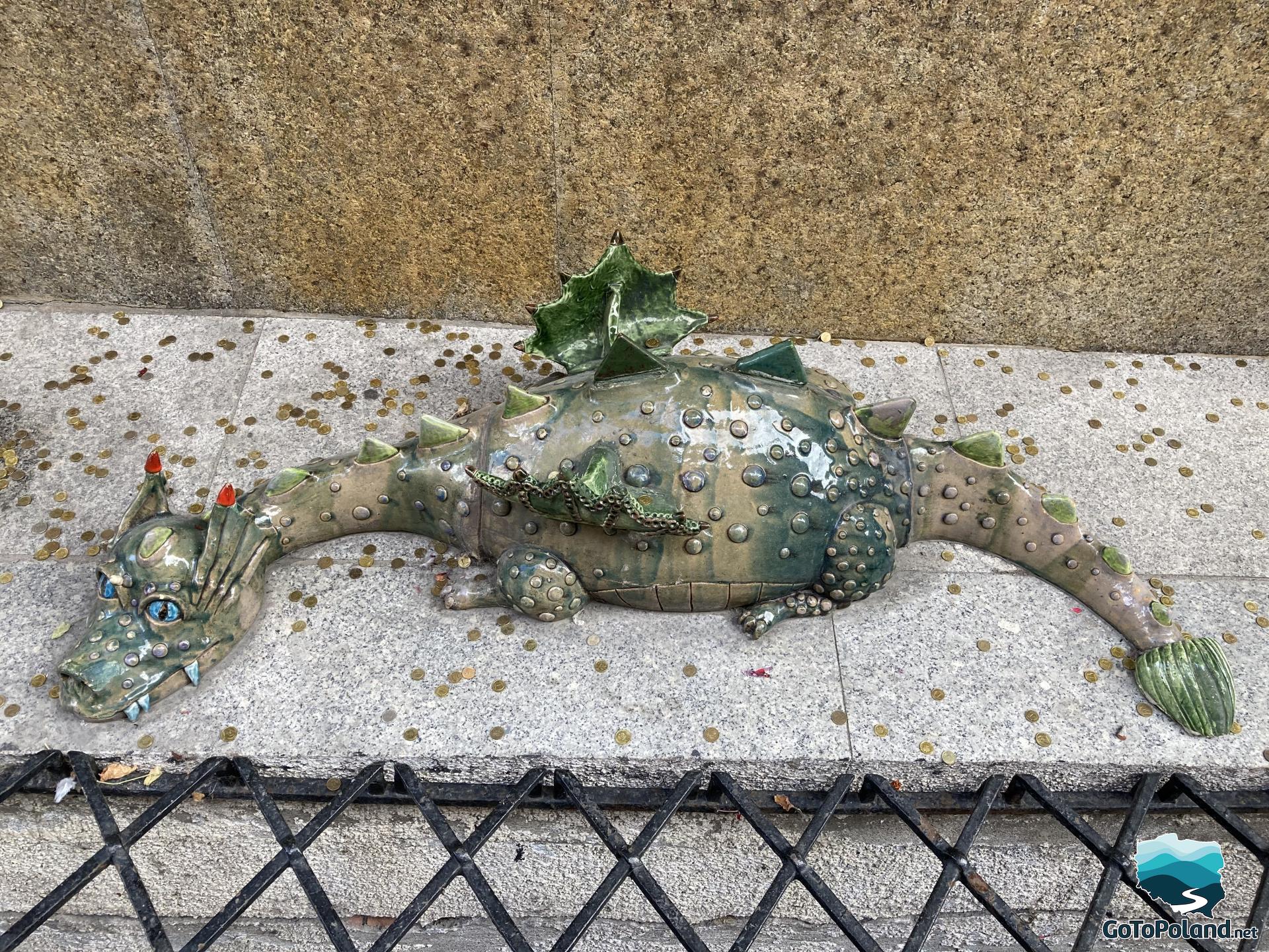 a statue of a small green dragon is lying on the ground