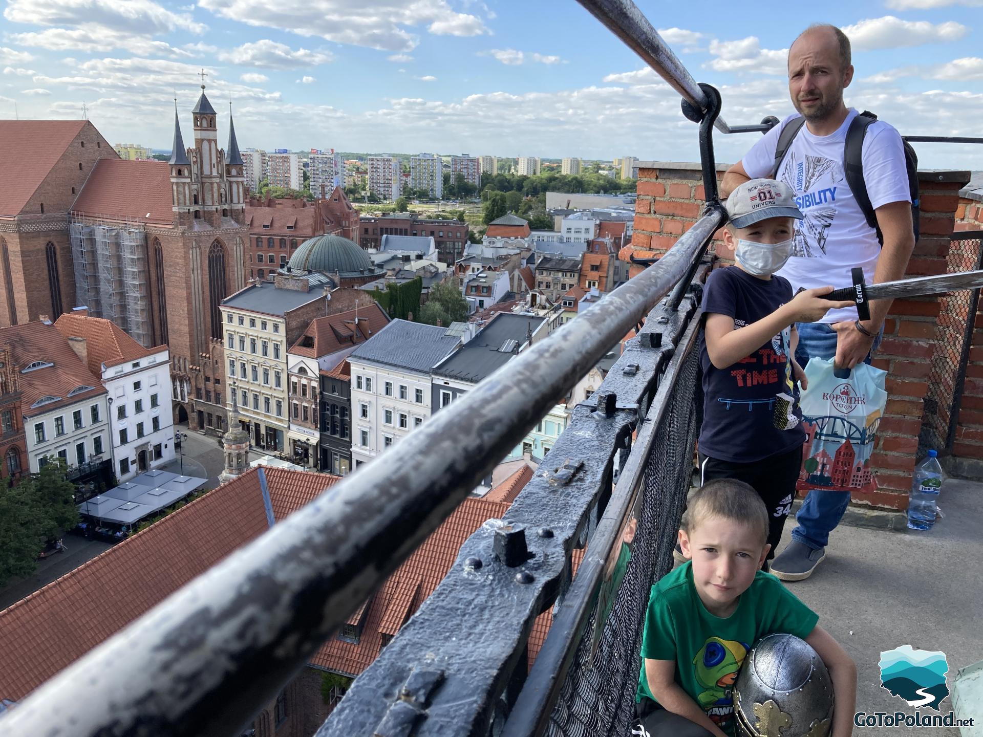 a man and two children are on top of the city hall watching the city skyline