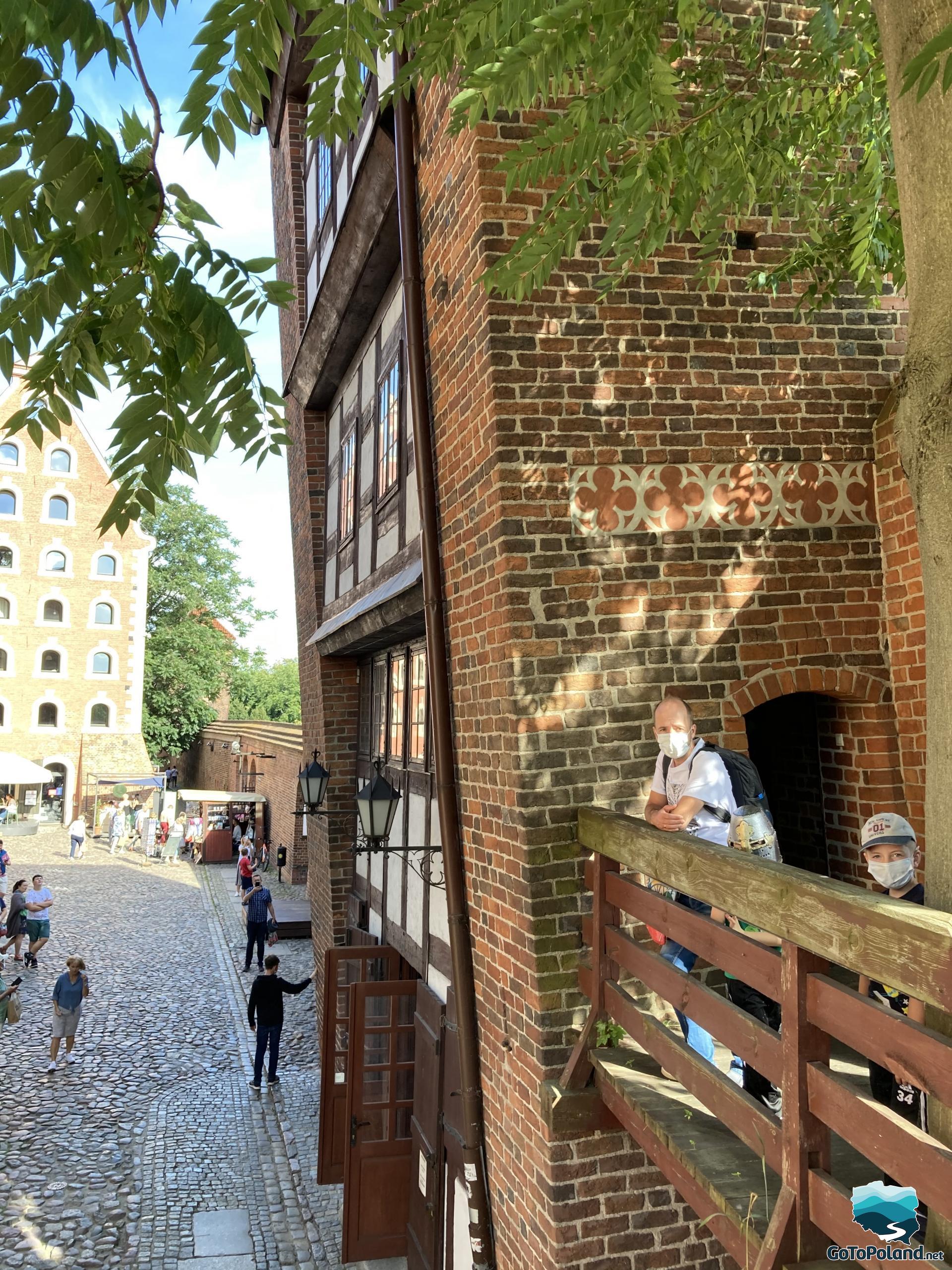 a man and two children are on a balcony that leads to a brick tower