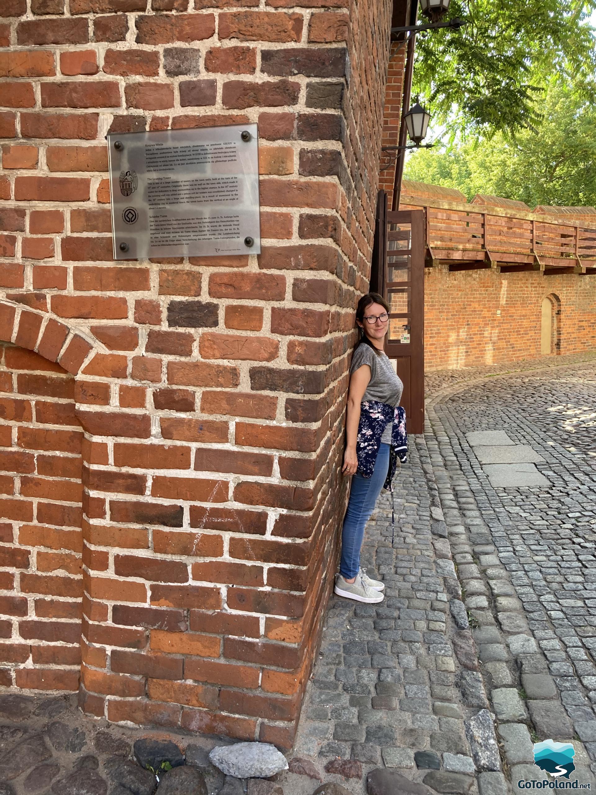 a woman is touching her back to a brick tower