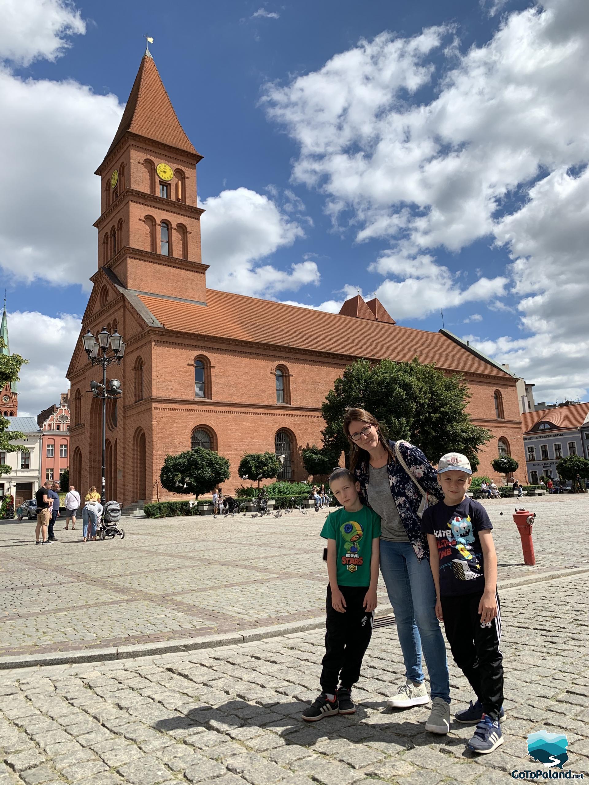 a woman and two children are standing on the main square behind them a historical building