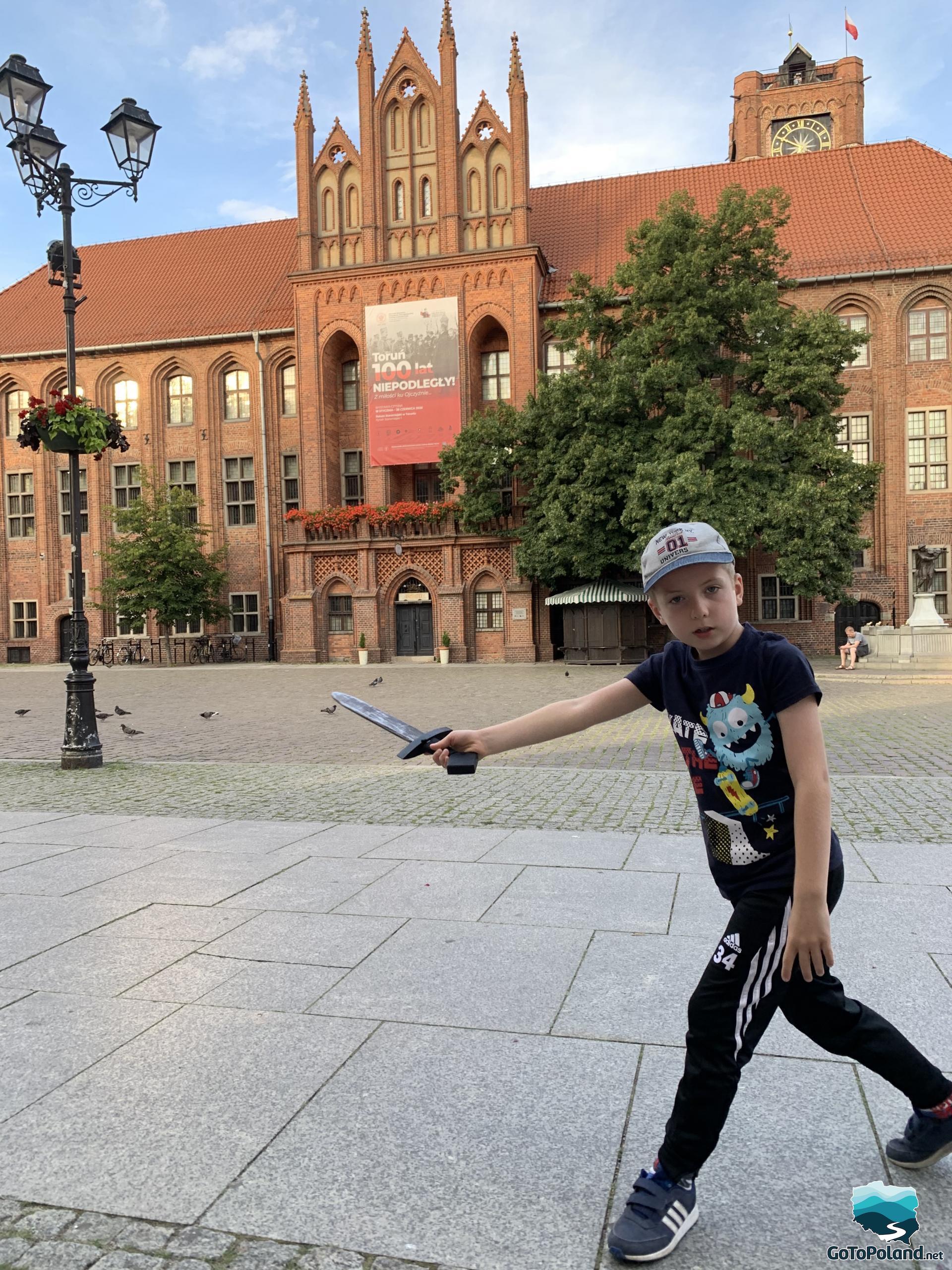 a boy is standing on the main square behind him a historical building