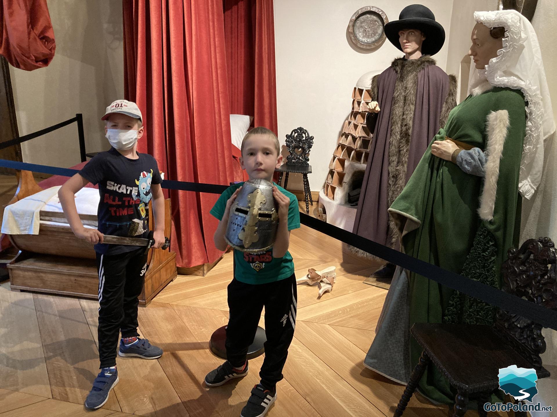 two boys are standing at the exhibition of medieval costumes