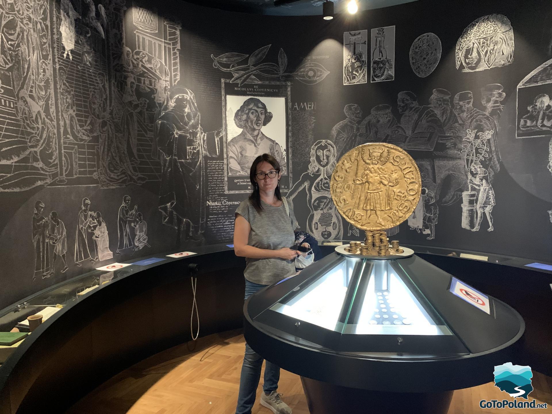 A woman is standing next to the exhibition about Copernicus