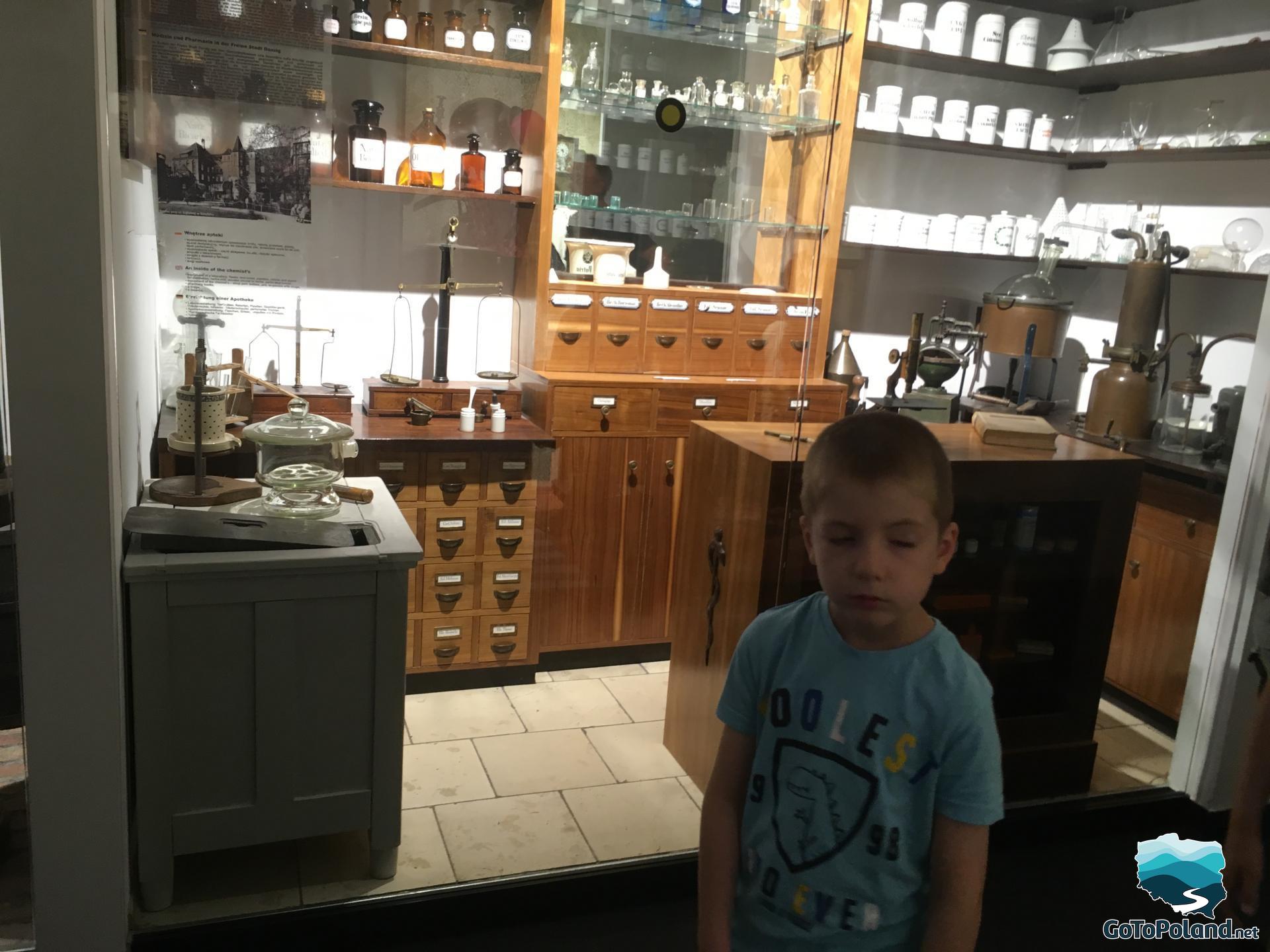 the exhibition shows an old pharmacy with many cabinets, glass containers and various utensils