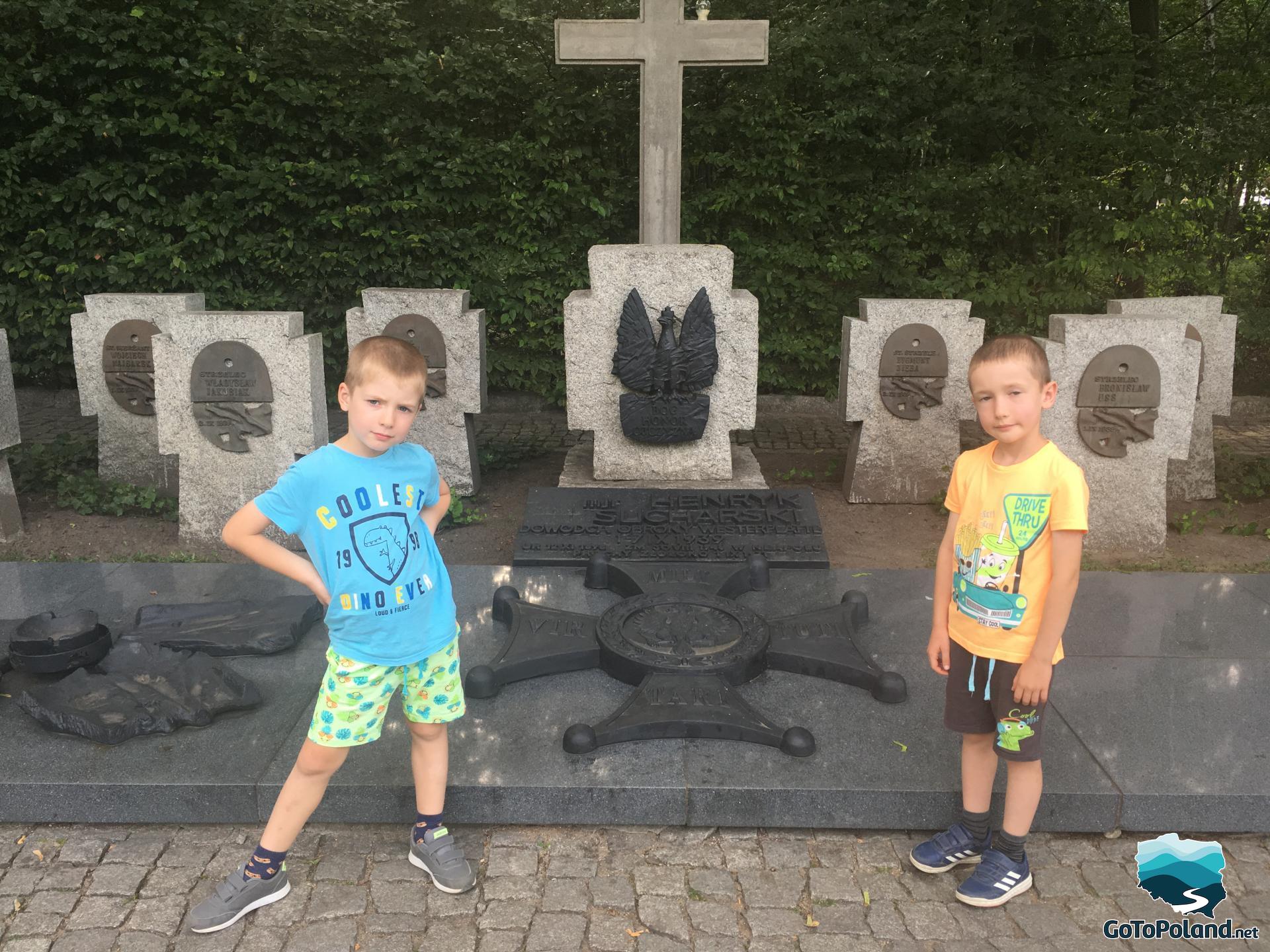 two children are standing near the graves of the defenders of Westerplatte