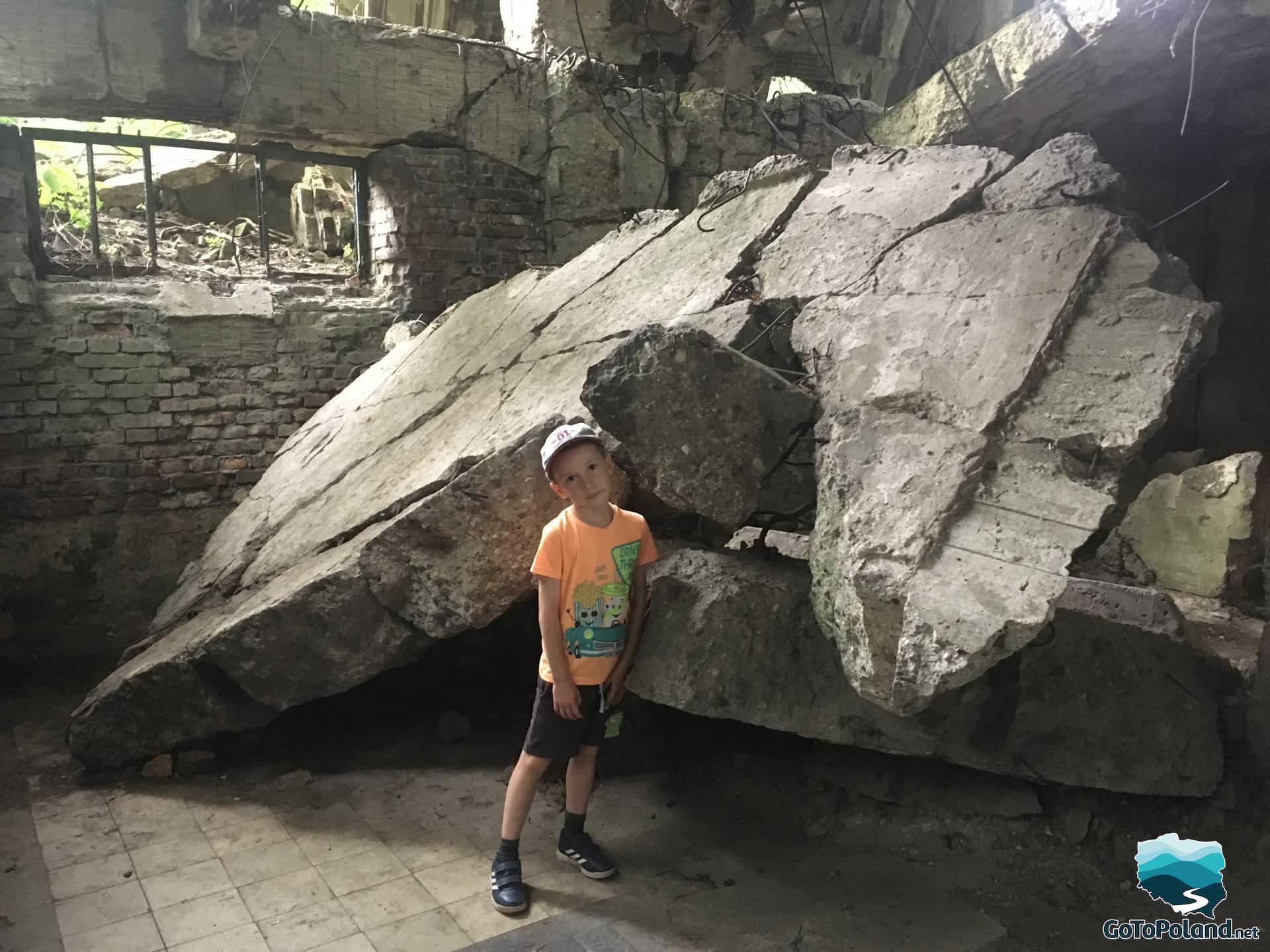 a boy is standing next to the ruins of the barracks