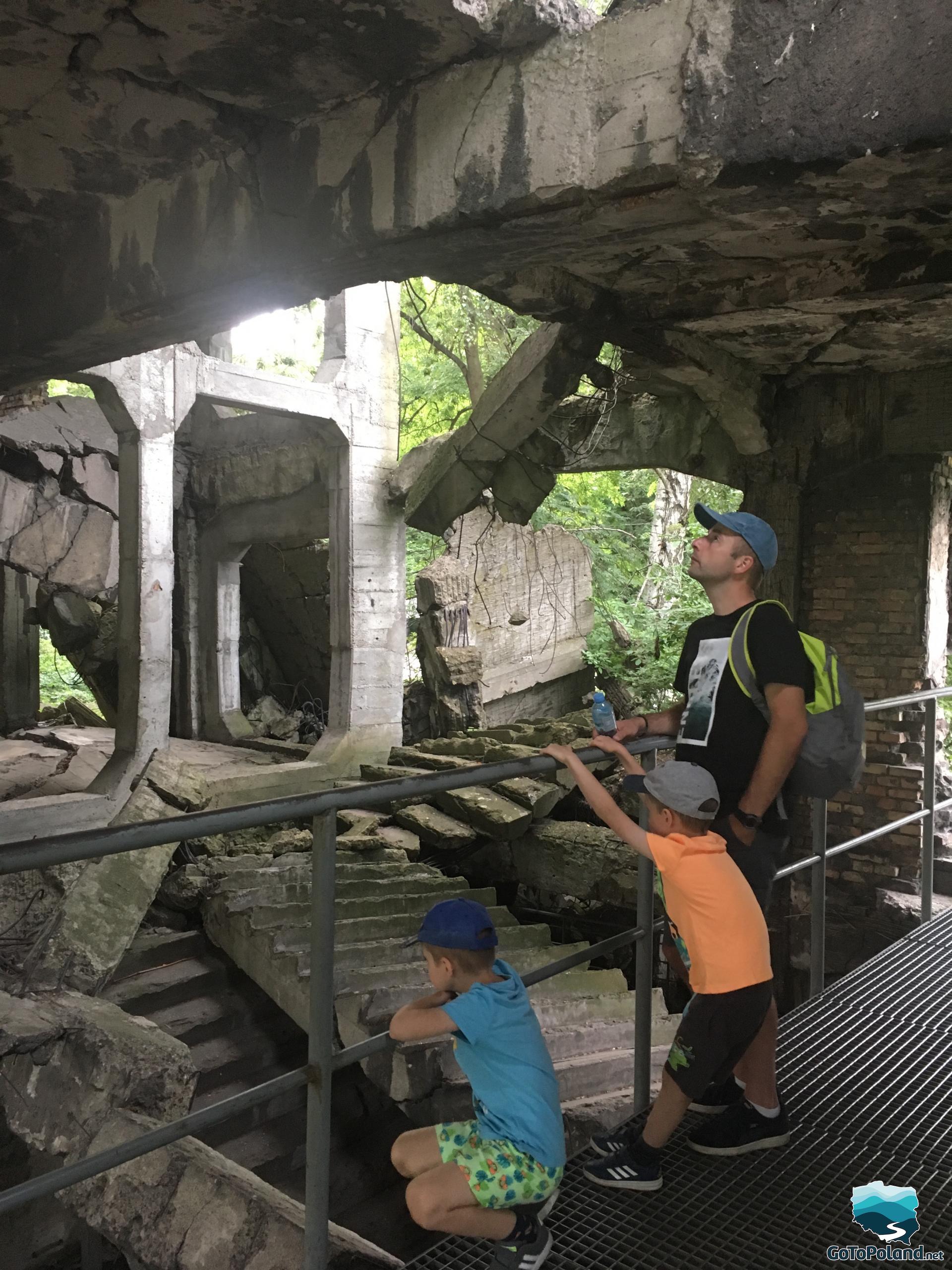 a man and two children are inside of the ruins of barracks