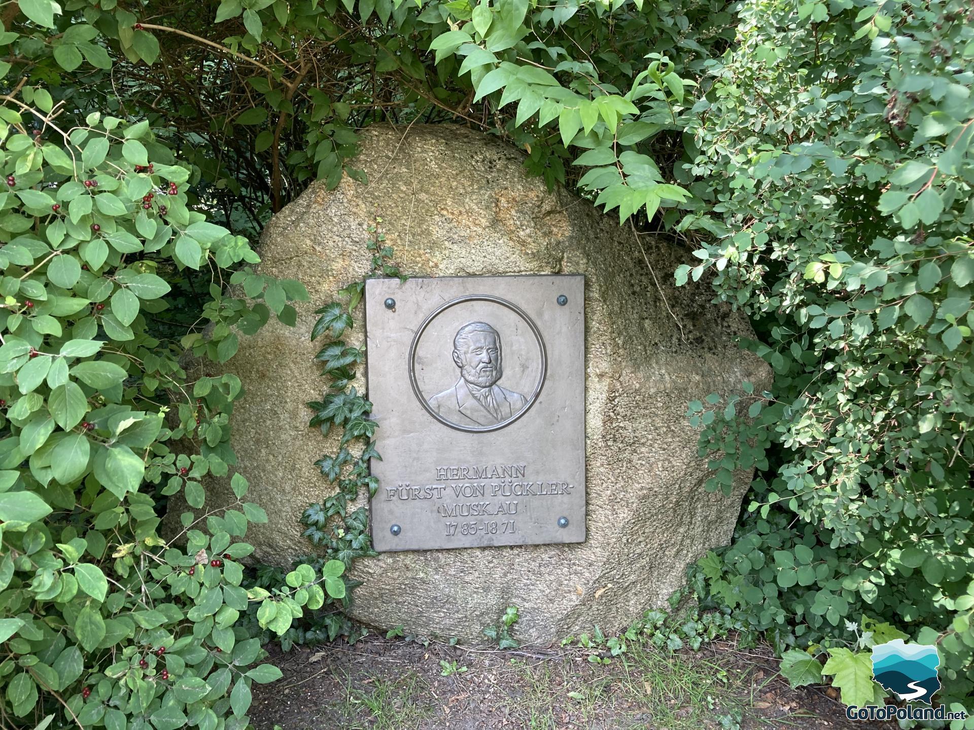 on the stone, there is a plaque with the name of the founder of the park