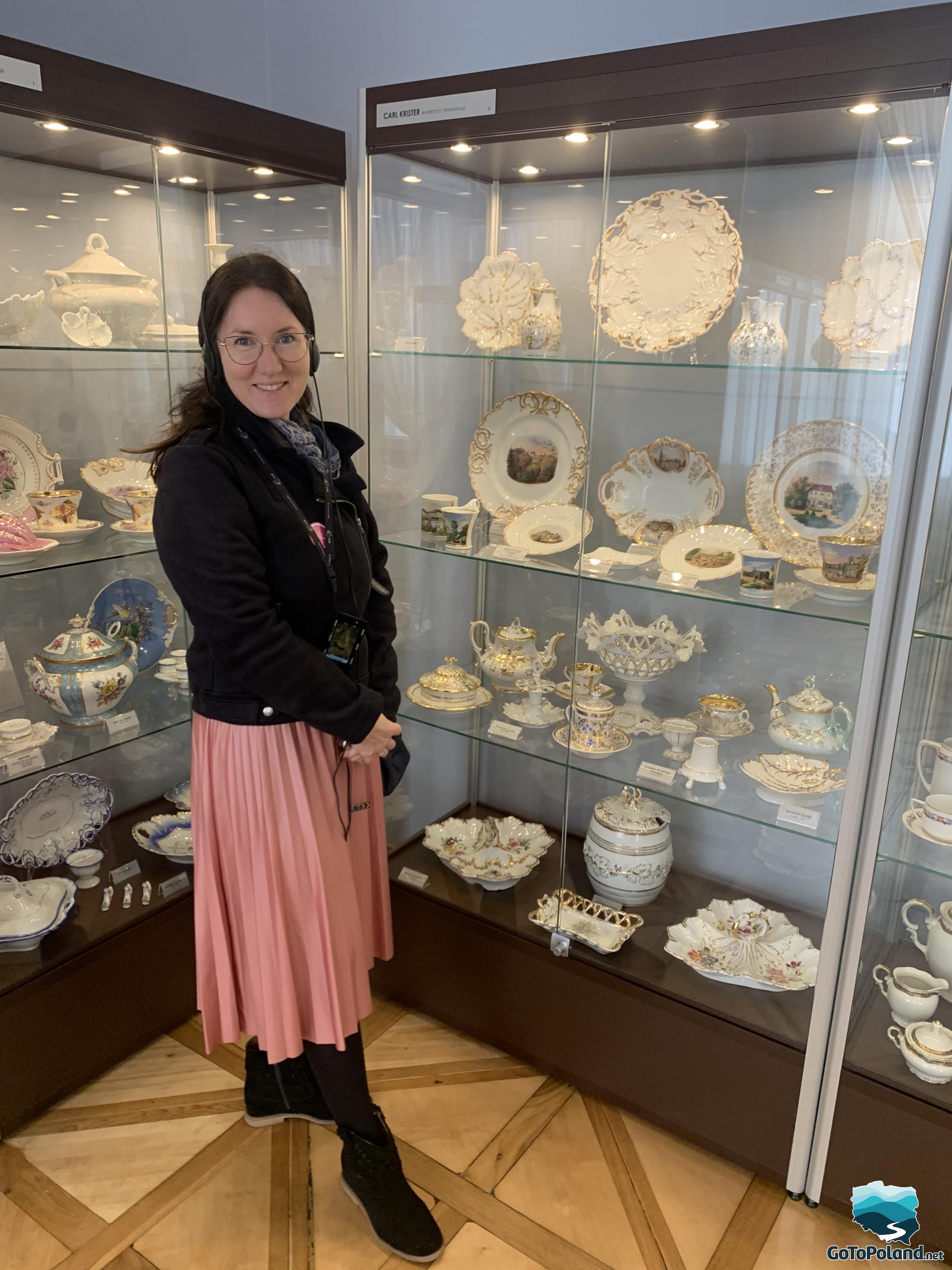 a woman is standing in front of a display case with porcelain objects
