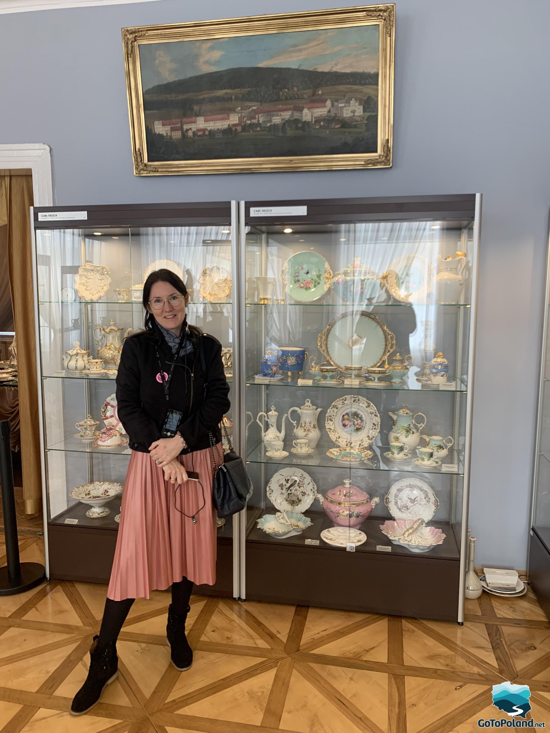 a woman is standing in front of a display case with porcelain objects