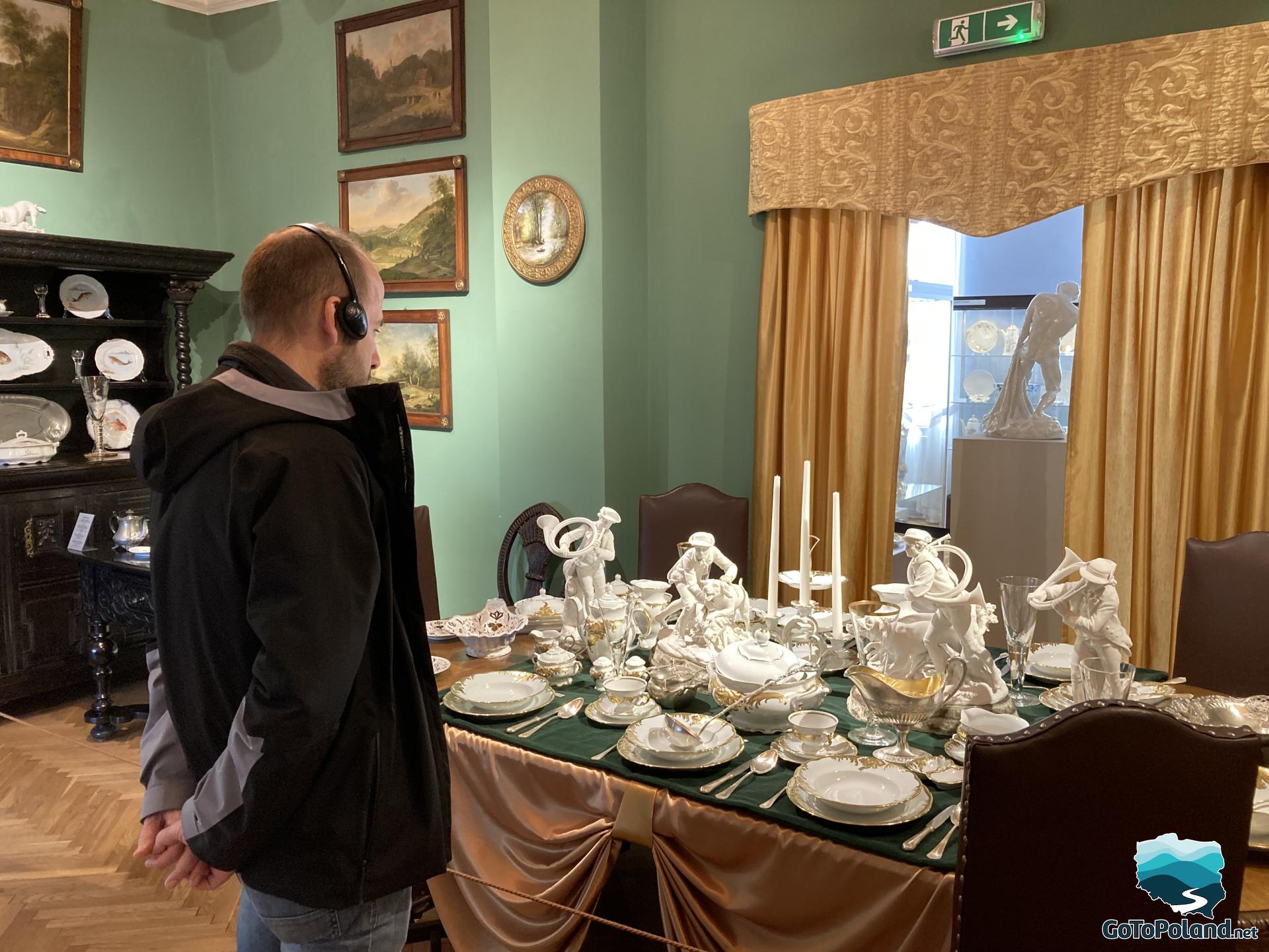 a man watching an exhibition about porcelain. The whole set is standing on the table. 