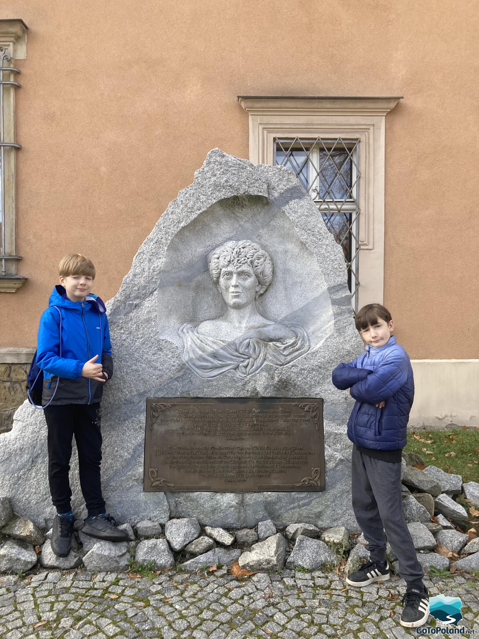 two children standing by a stone carving of a bust of a woman