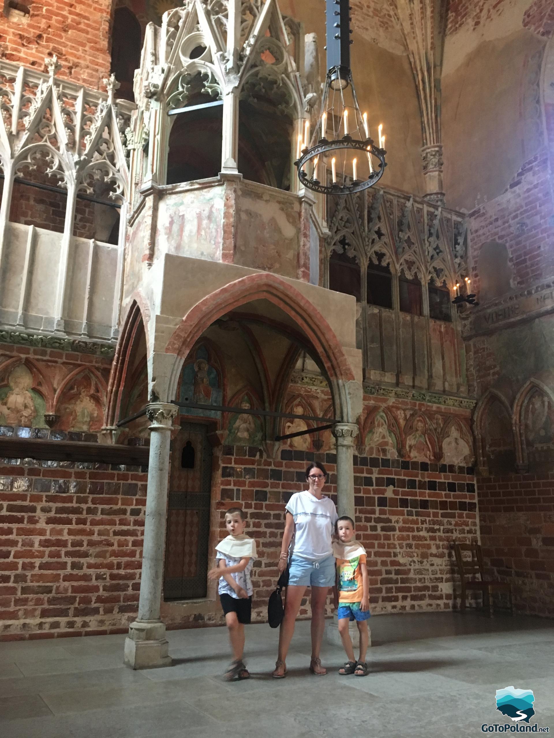 two boys and a woman are standing in a church of the castle