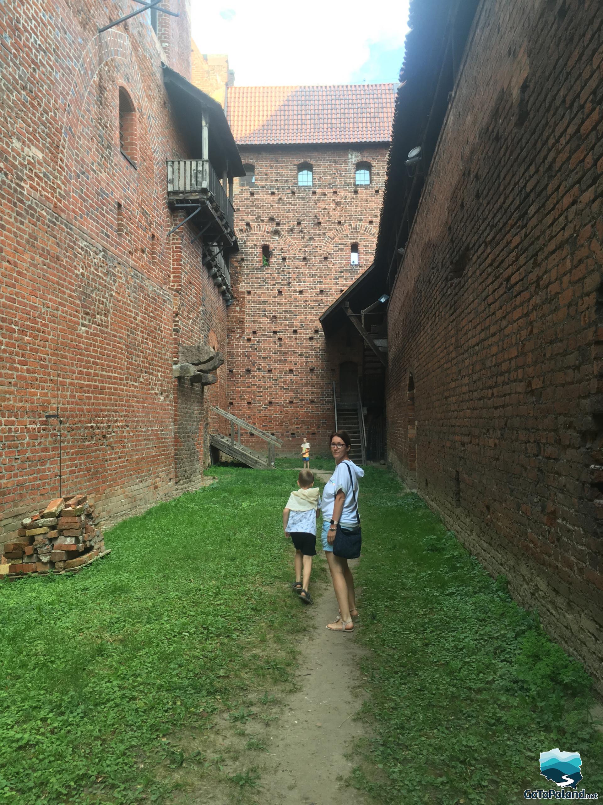 woman and boys are walking between the castle walls