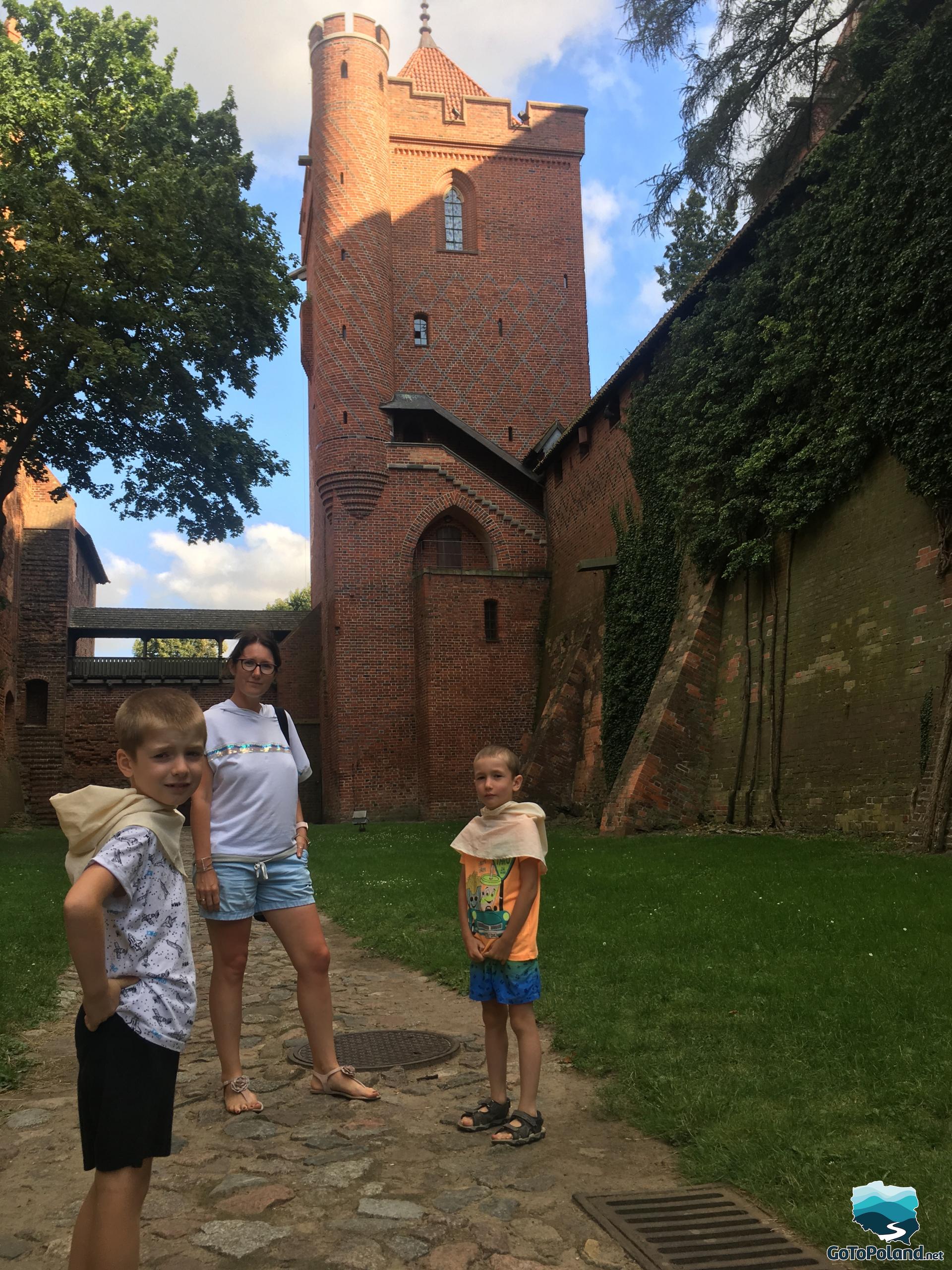 woman and boys are standing near the castle walls