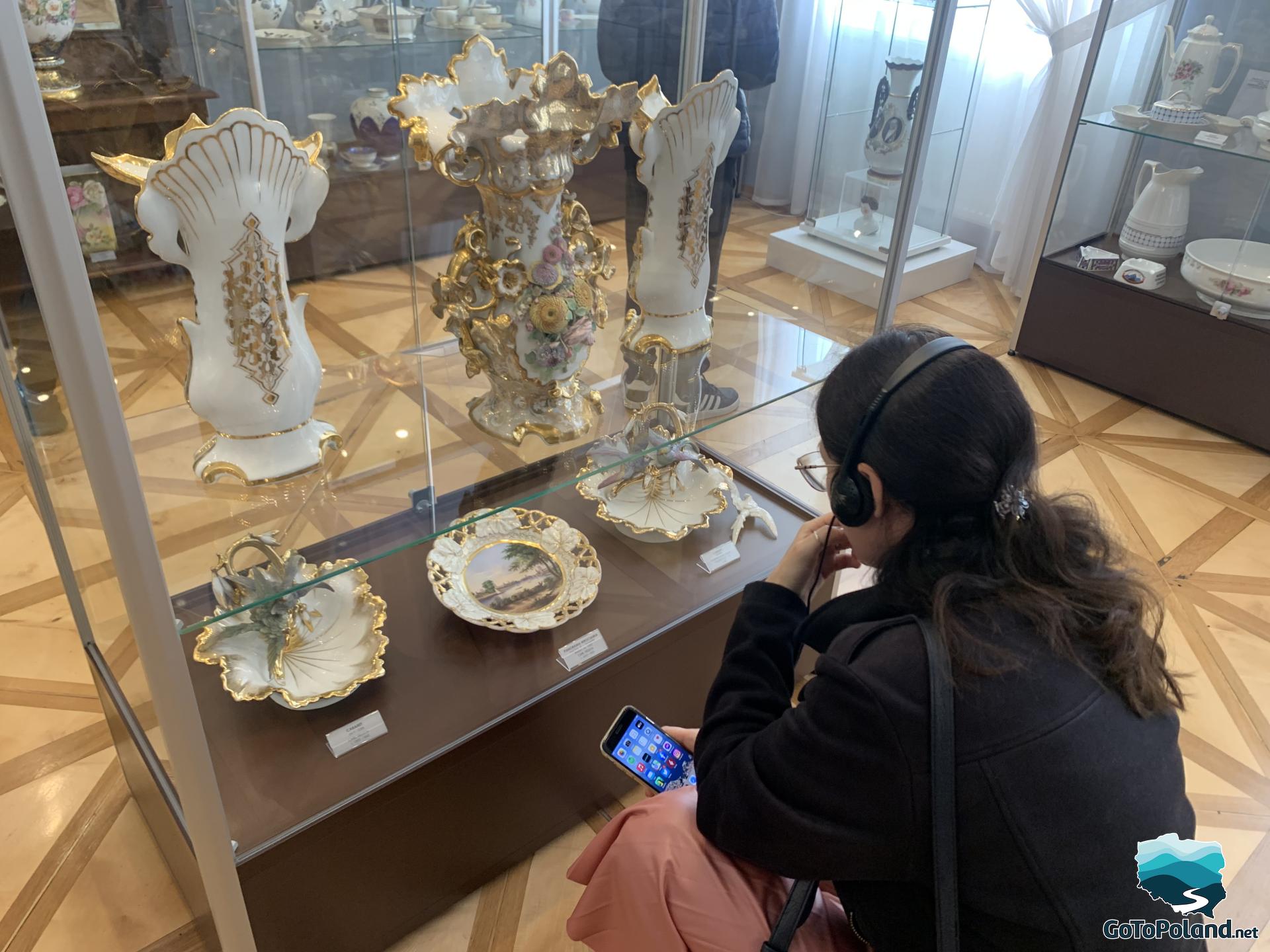 a woman looking at the porcelain items