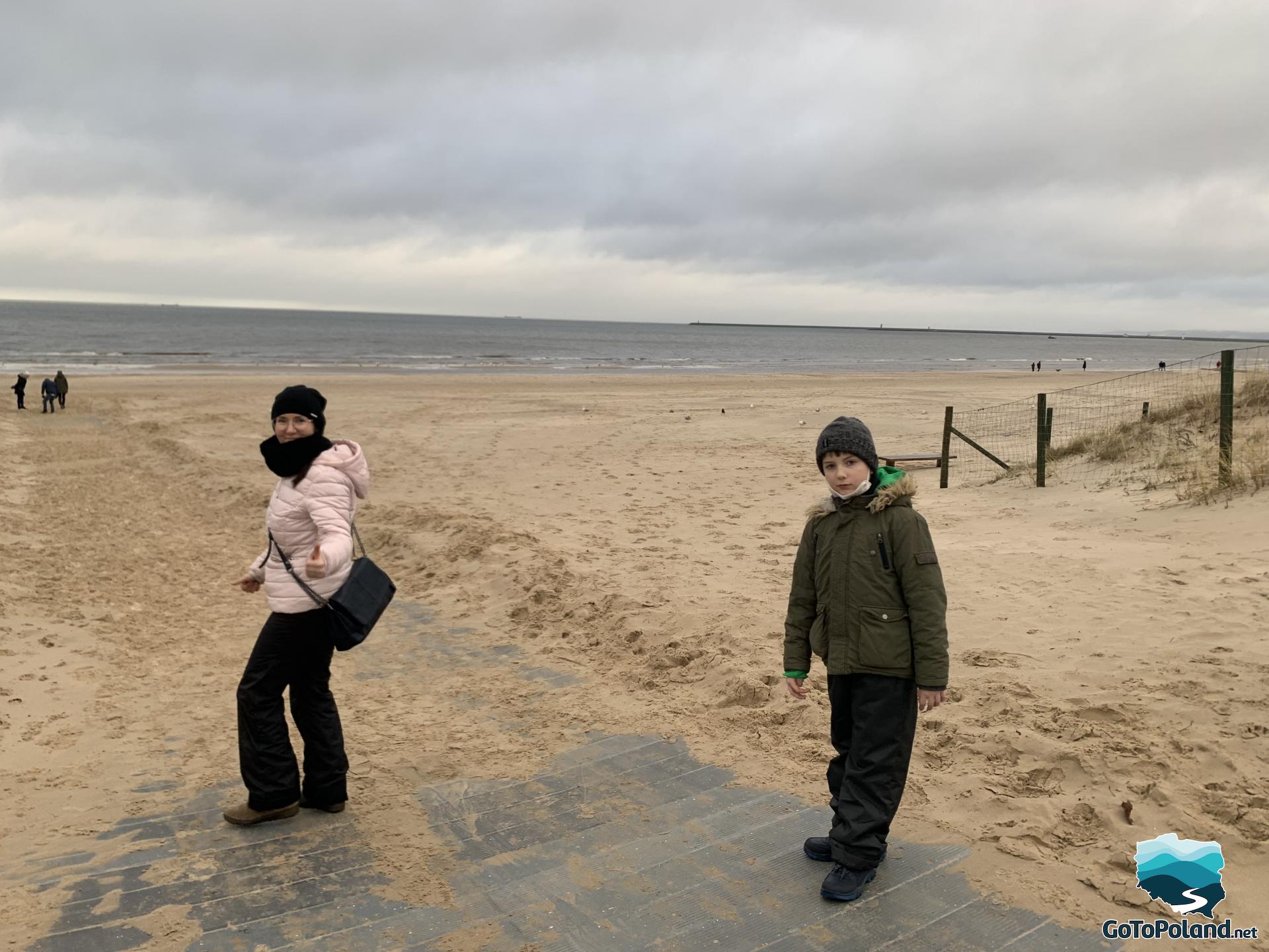 a woman and a boy are walking on a beach
