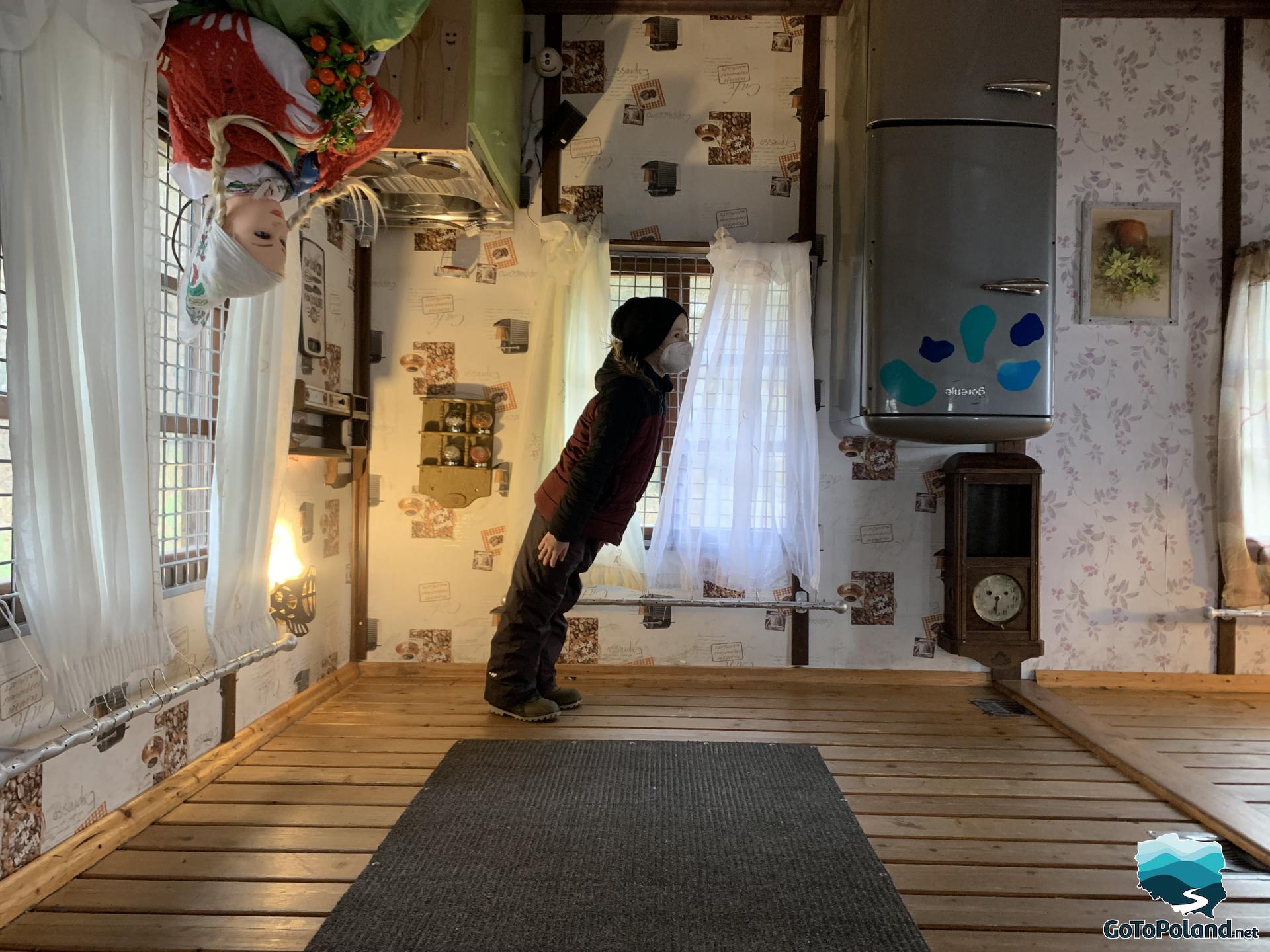 the boy is standing in a cottage that is upside down