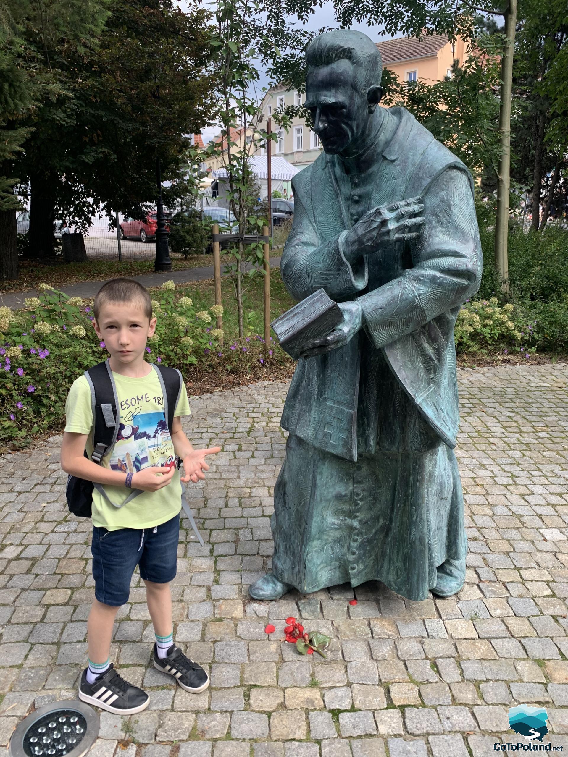 A boy next to the monument of parish priest