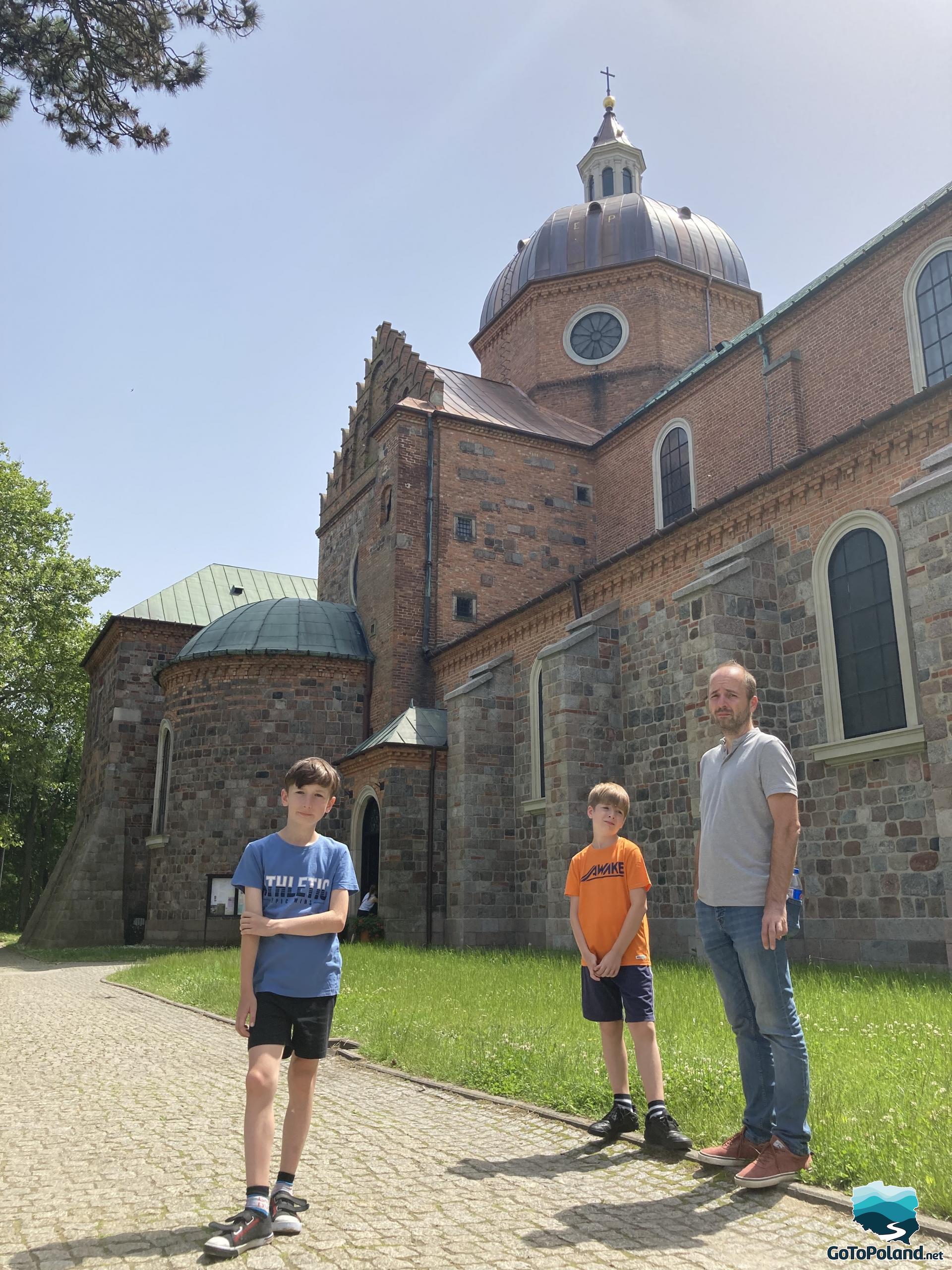 A man and two young boys standing next to the church