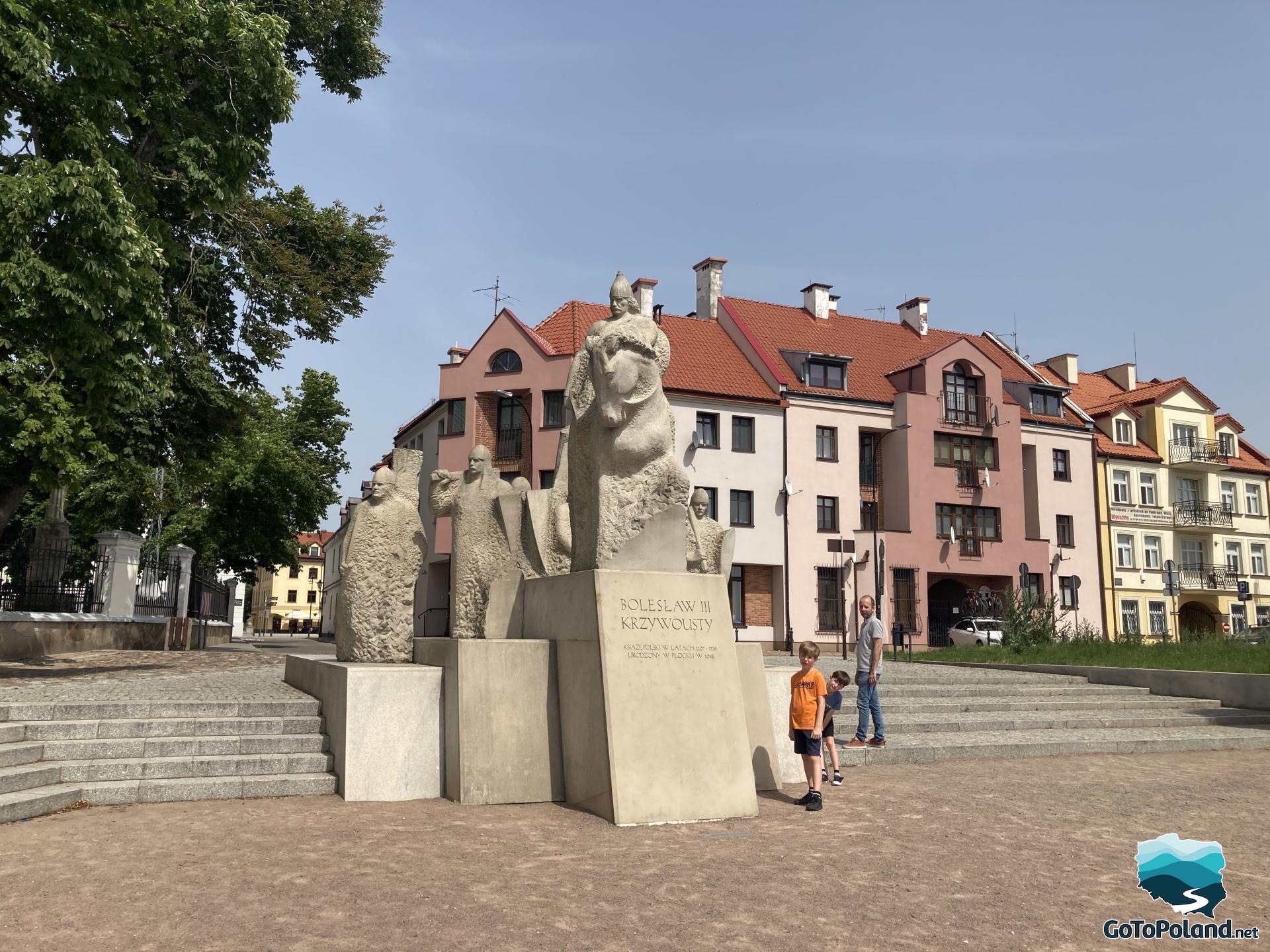 A sculpture that presents a polish ruler on his horse, tenement houses in the background 